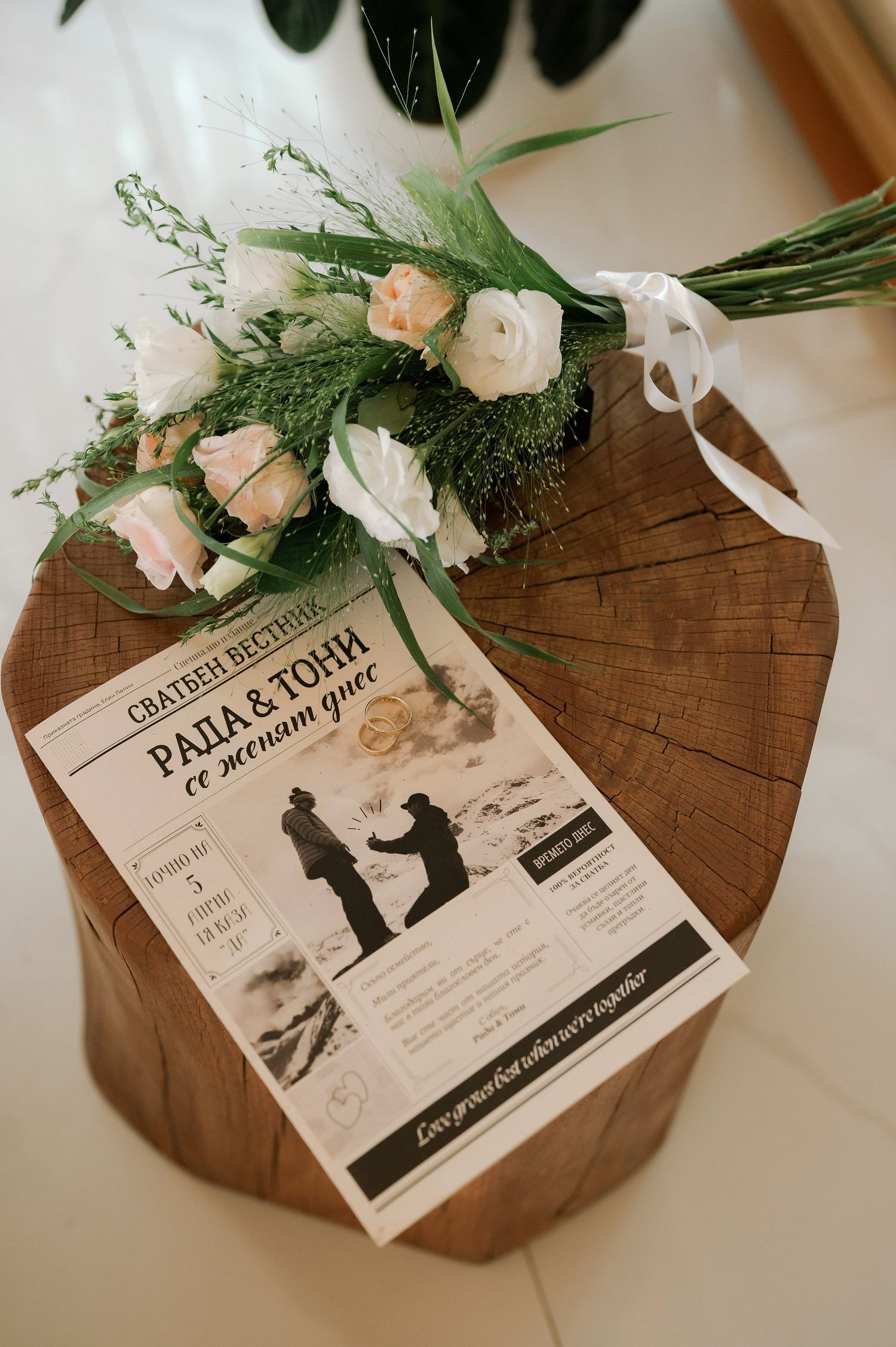 Wedding invitation cards with floral decorations displayed on a wooden surface with roses and greenery.