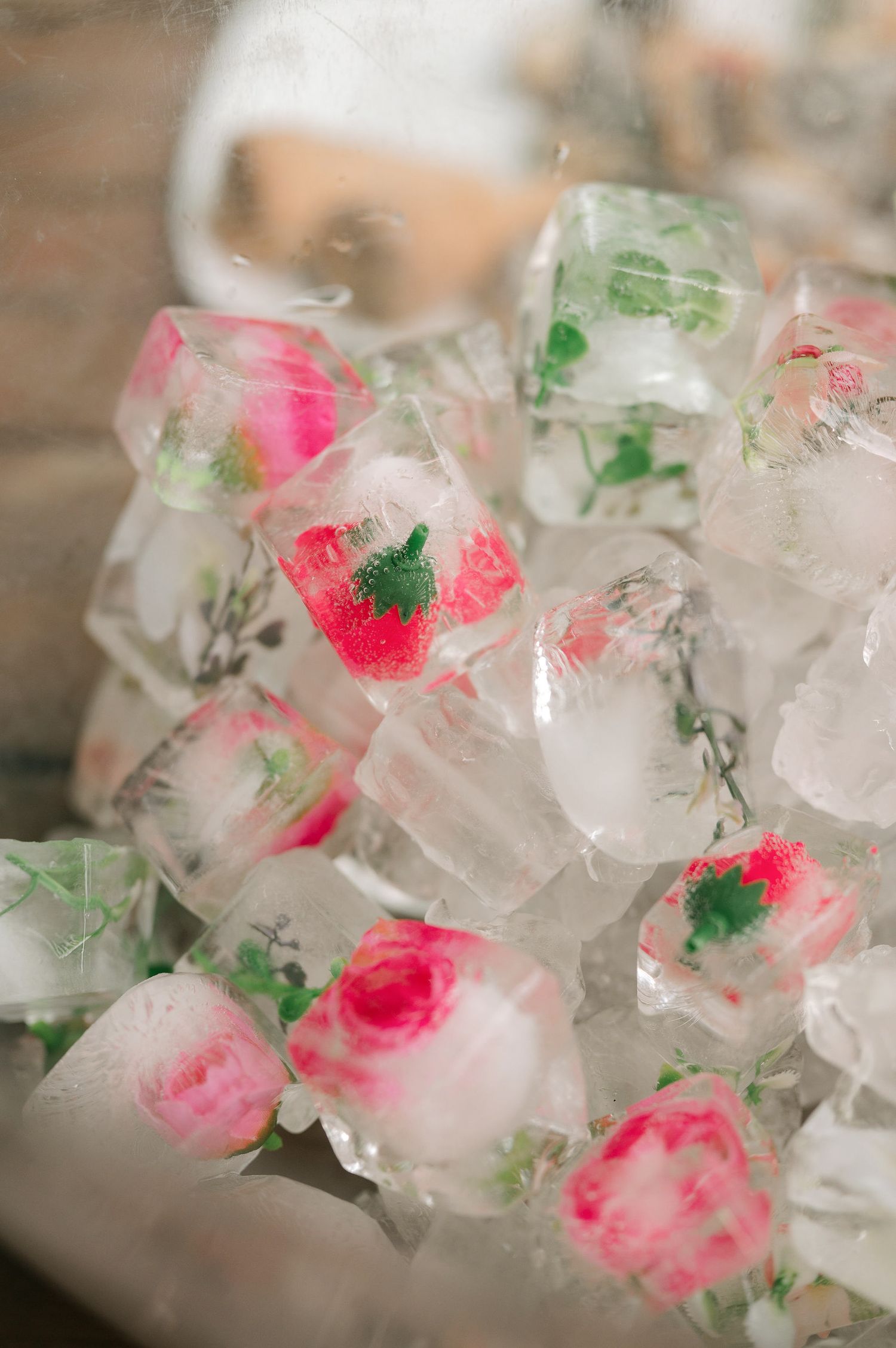 Frozen ice cubes with pink and green floral elements create an artistic display of botanical elements trapped in ice.
