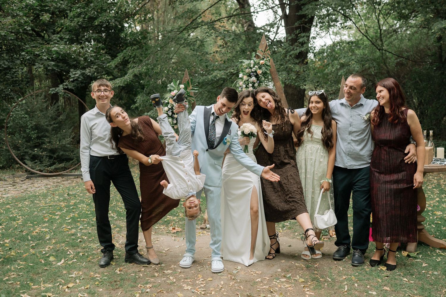 A group of wedding guests walk together through a lush garden setting during an outdoor celebration.