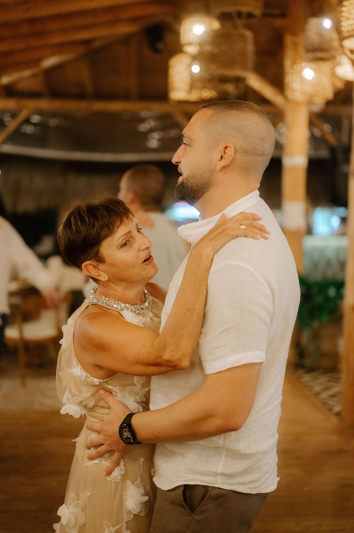 A couple in wedding attire dances intimately together in a warmly lit indoor venue.
