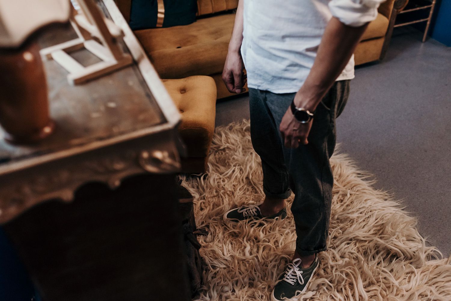 Straw scattered on dark floor near person wearing jeans and sneakers.
