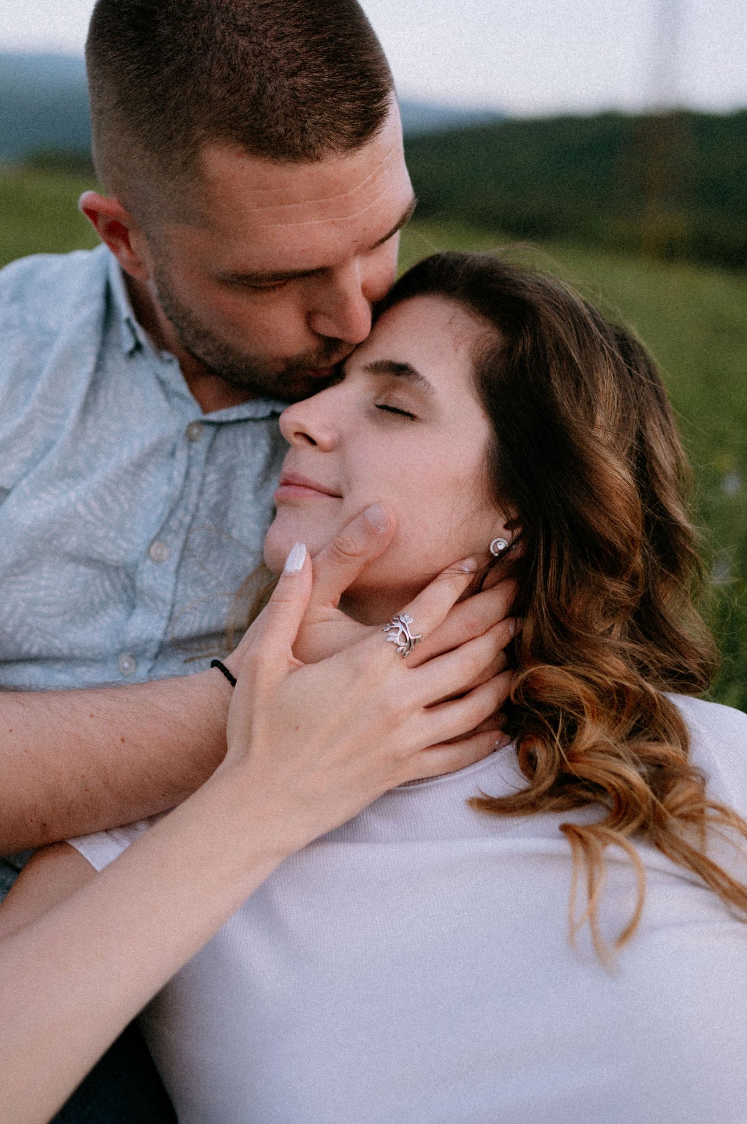 An intimate close-up of two people sharing a tender moment outdoors.