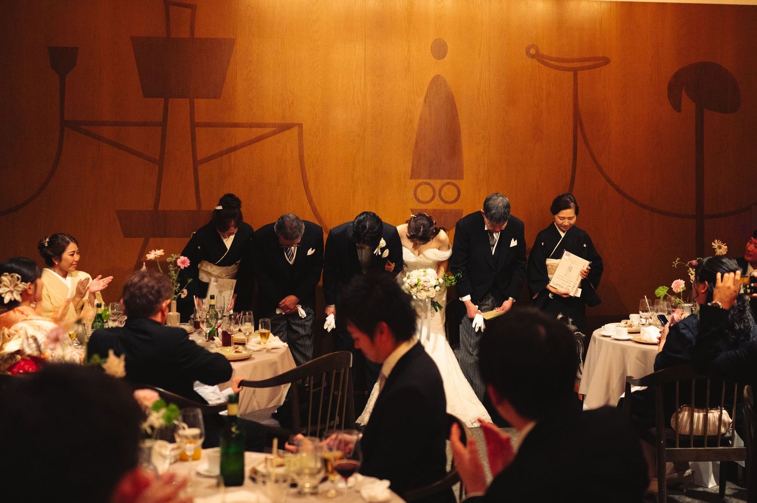 Warm-lit banquet hall with guests seated at round tables for formal dinner event.