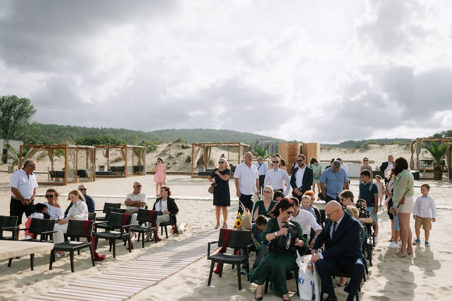 Guests gather on an outdoor patio venue with chairs set up for a seaside event under cloudy skies.