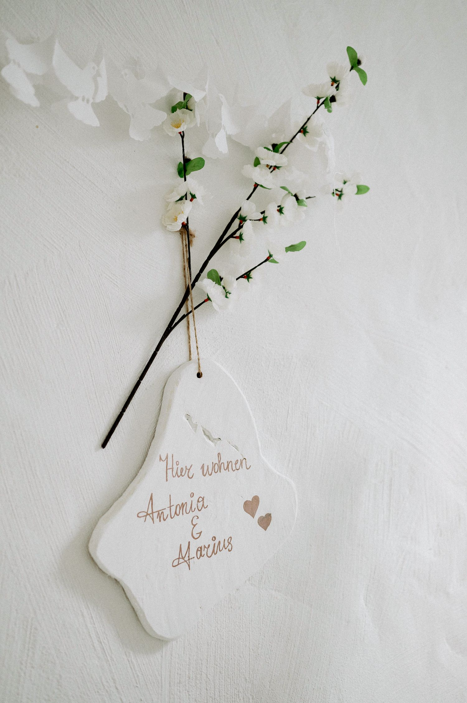 White decorative tags with handwritten text hanging from branches with green leaves.