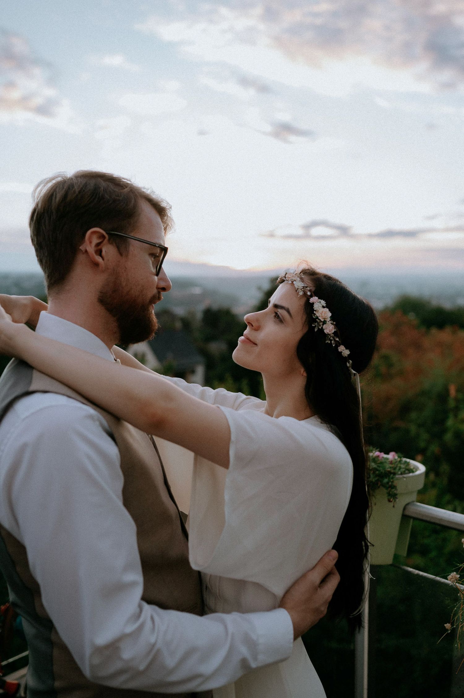 A tender embrace between newlyweds on a balcony during sunset.