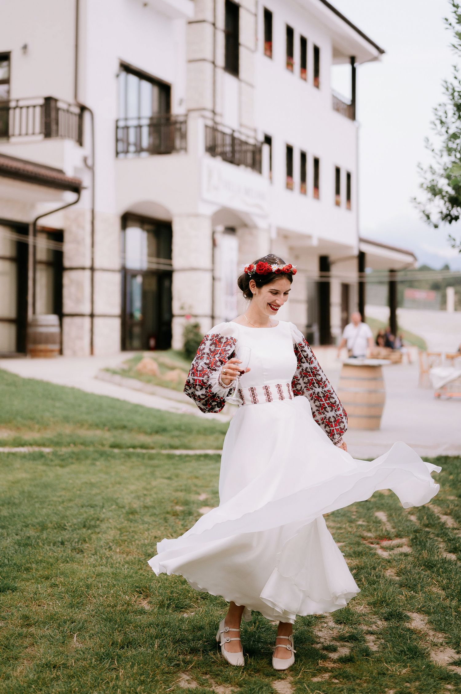 White dress with traditional embroidery twirling in front of modern building.
