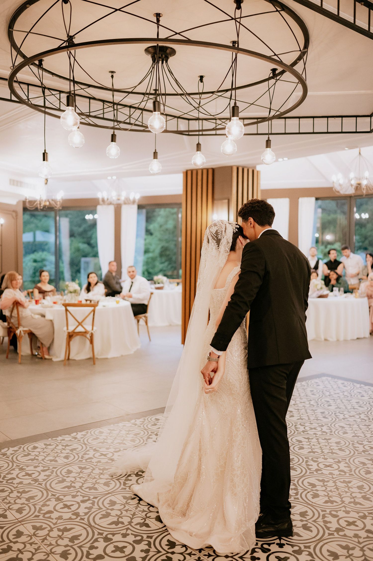 Wedding reception ballroom with ornate floor pattern and modern lighting fixtures.