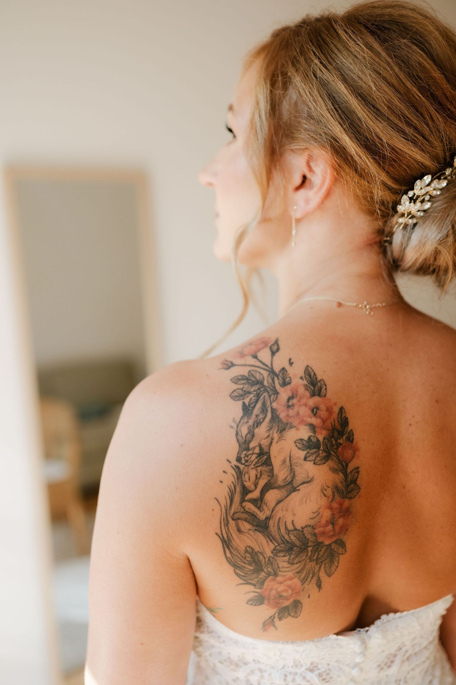 Detailed view of an intricate floral tattoo on shoulder with white lace dress.
