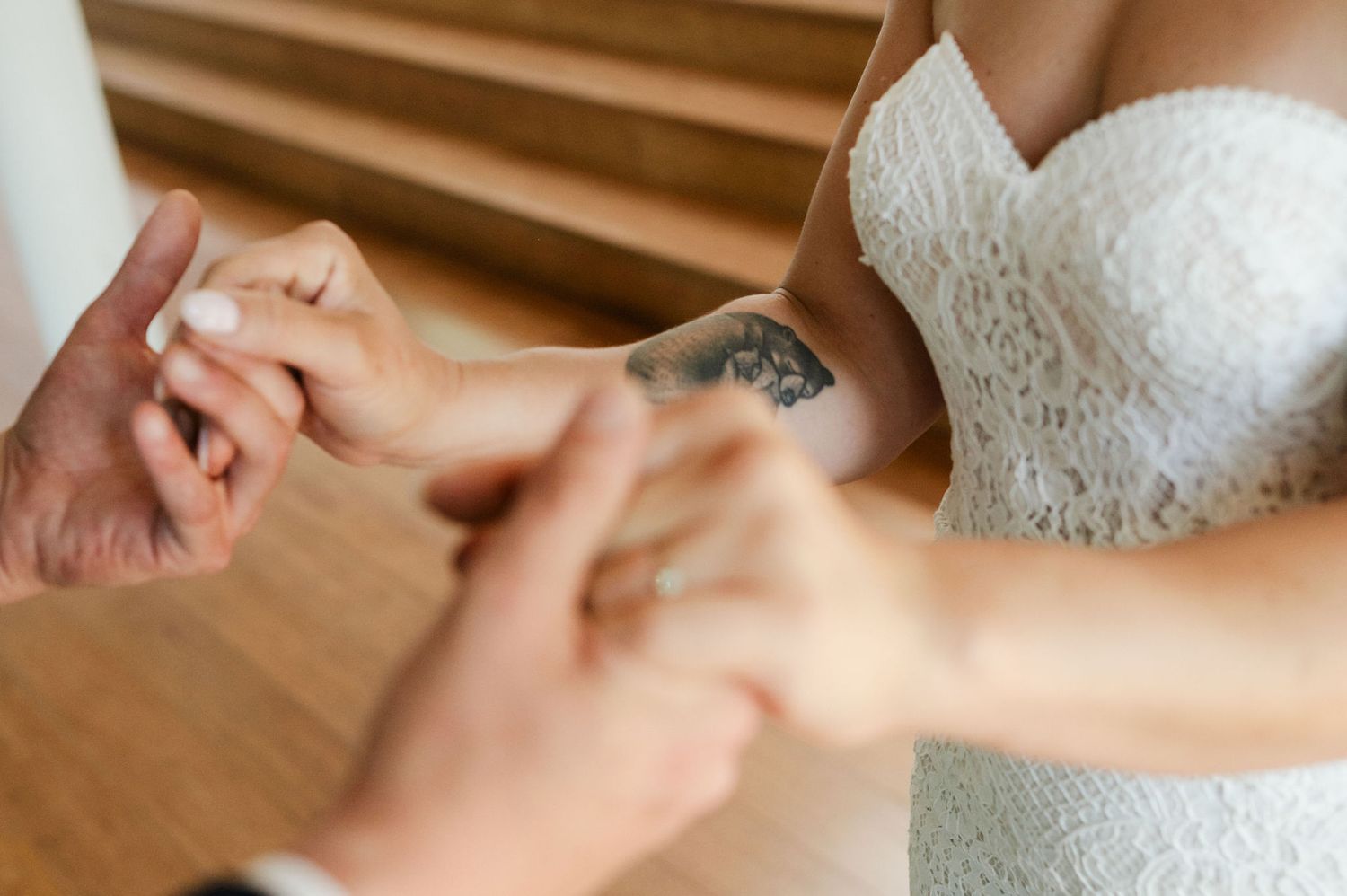 Close-up shot of bride's lace wedding dress train on hardwood floor.