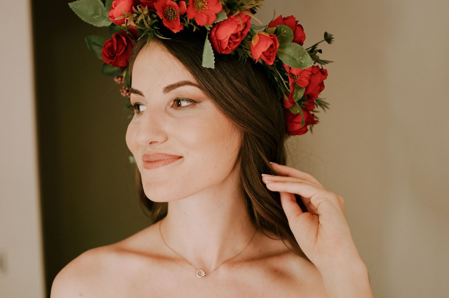 Red rose flower crown detail with green foliage against neutral background.