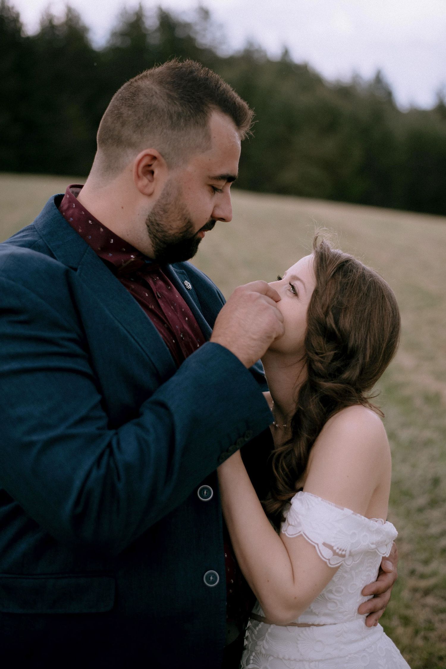 A romantic moment shared between a couple on a hillside during their wedding day.