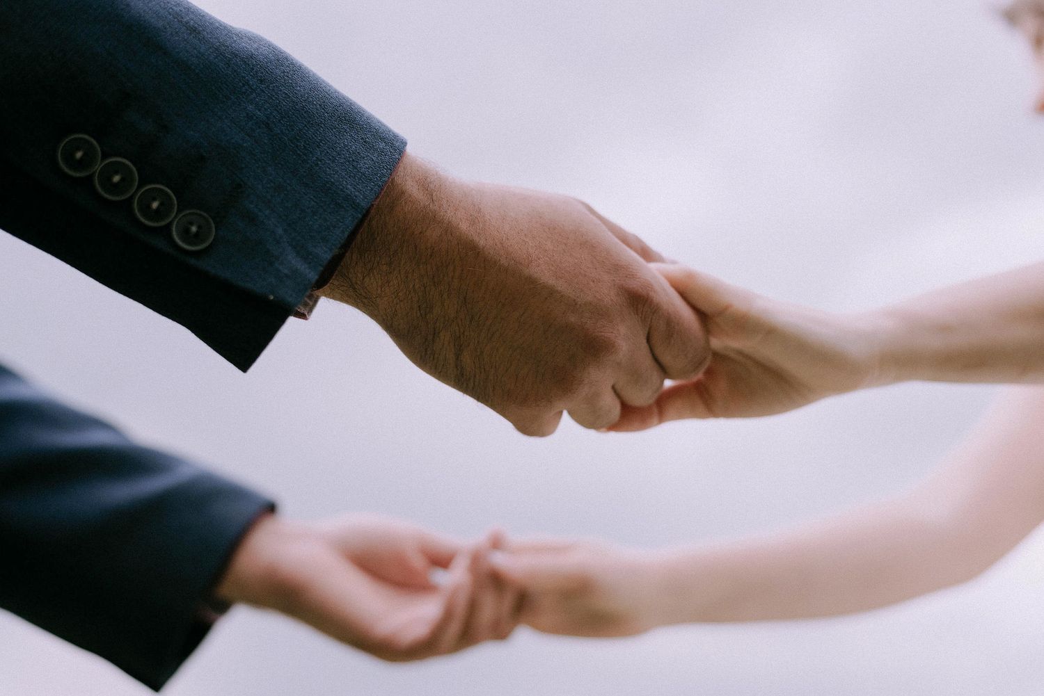 Close-up shot of hands reaching towards each other in a tender moment.