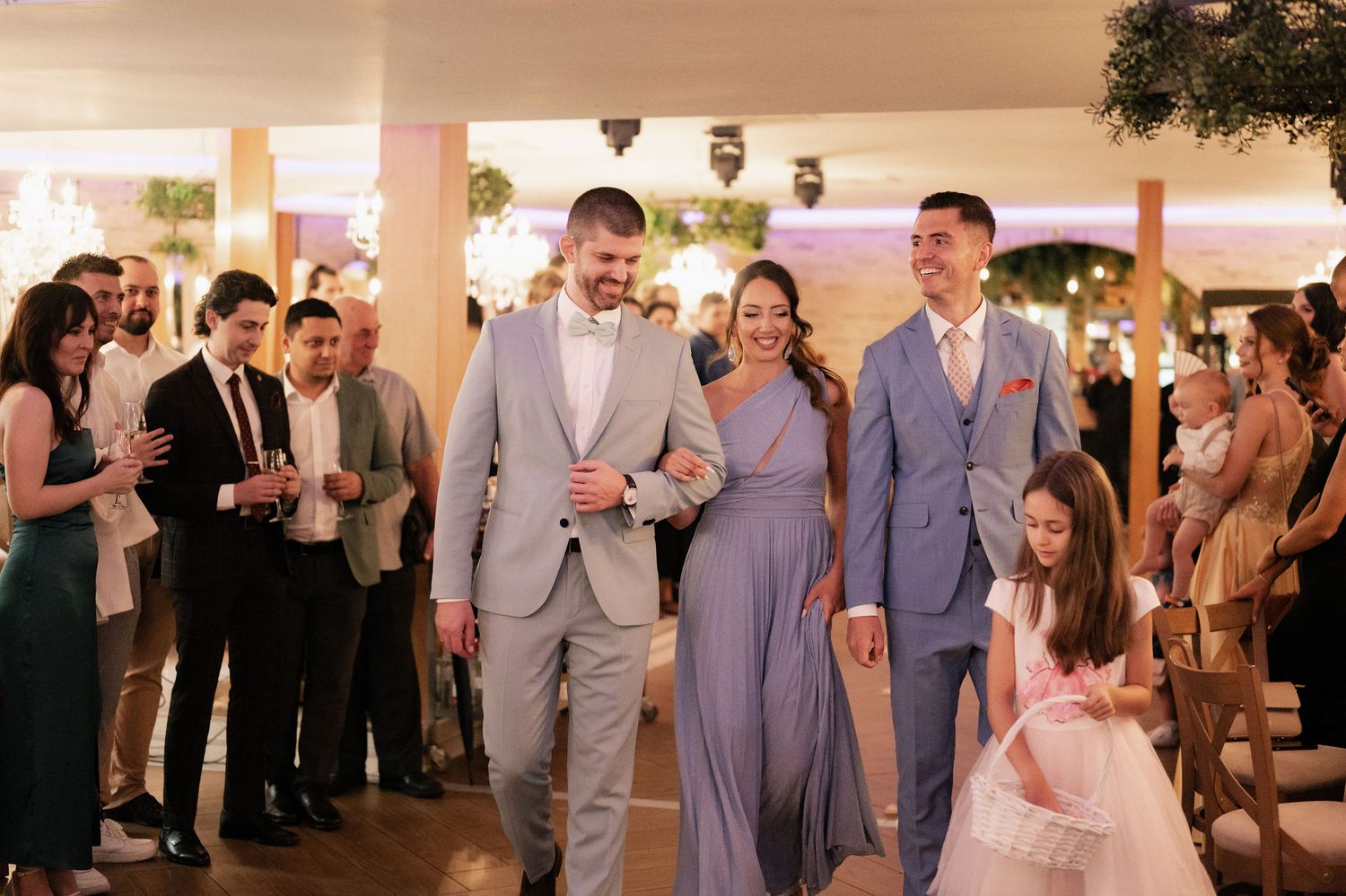 Wedding guests dance and celebrate during an evening reception in a warmly lit indoor venue.