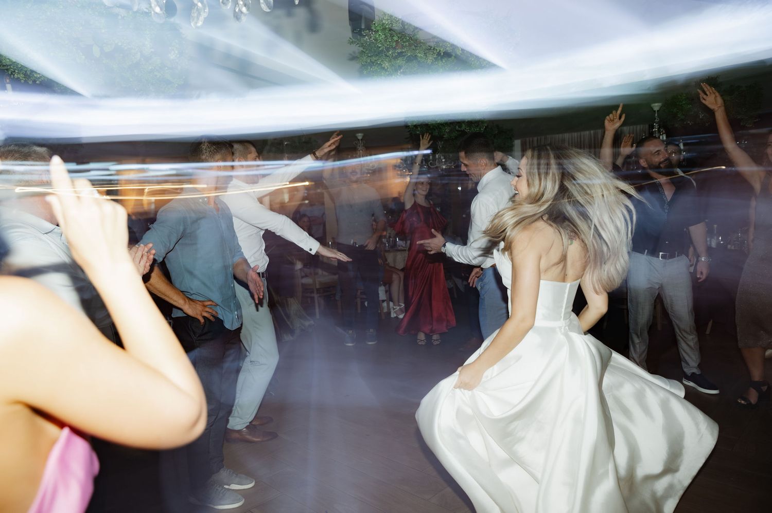 People dancing together in a ballroom with elegant formal attire and decorative lighting.