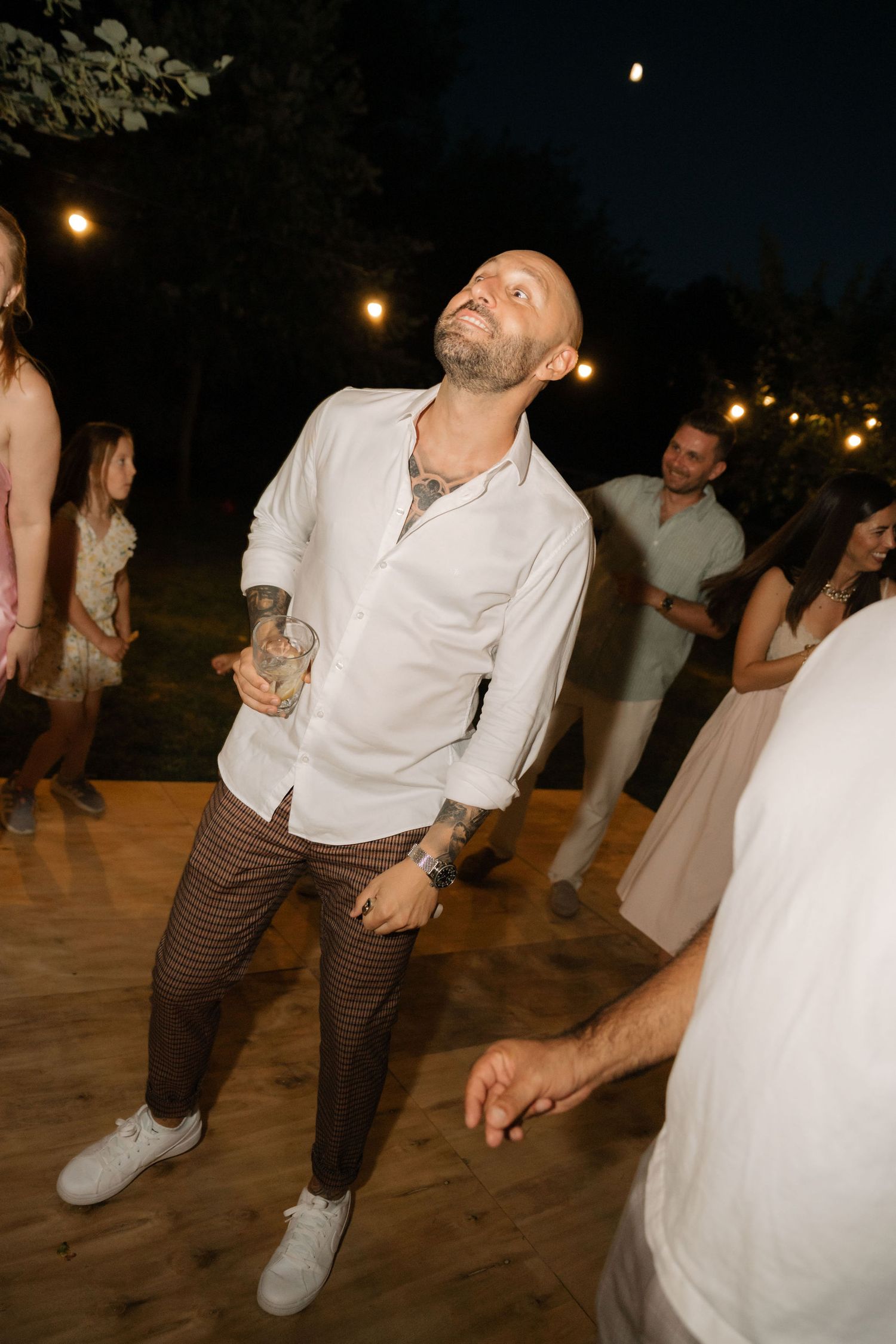 Dancers performing energetic moves on an outdoor wooden dance floor during an evening celebration.