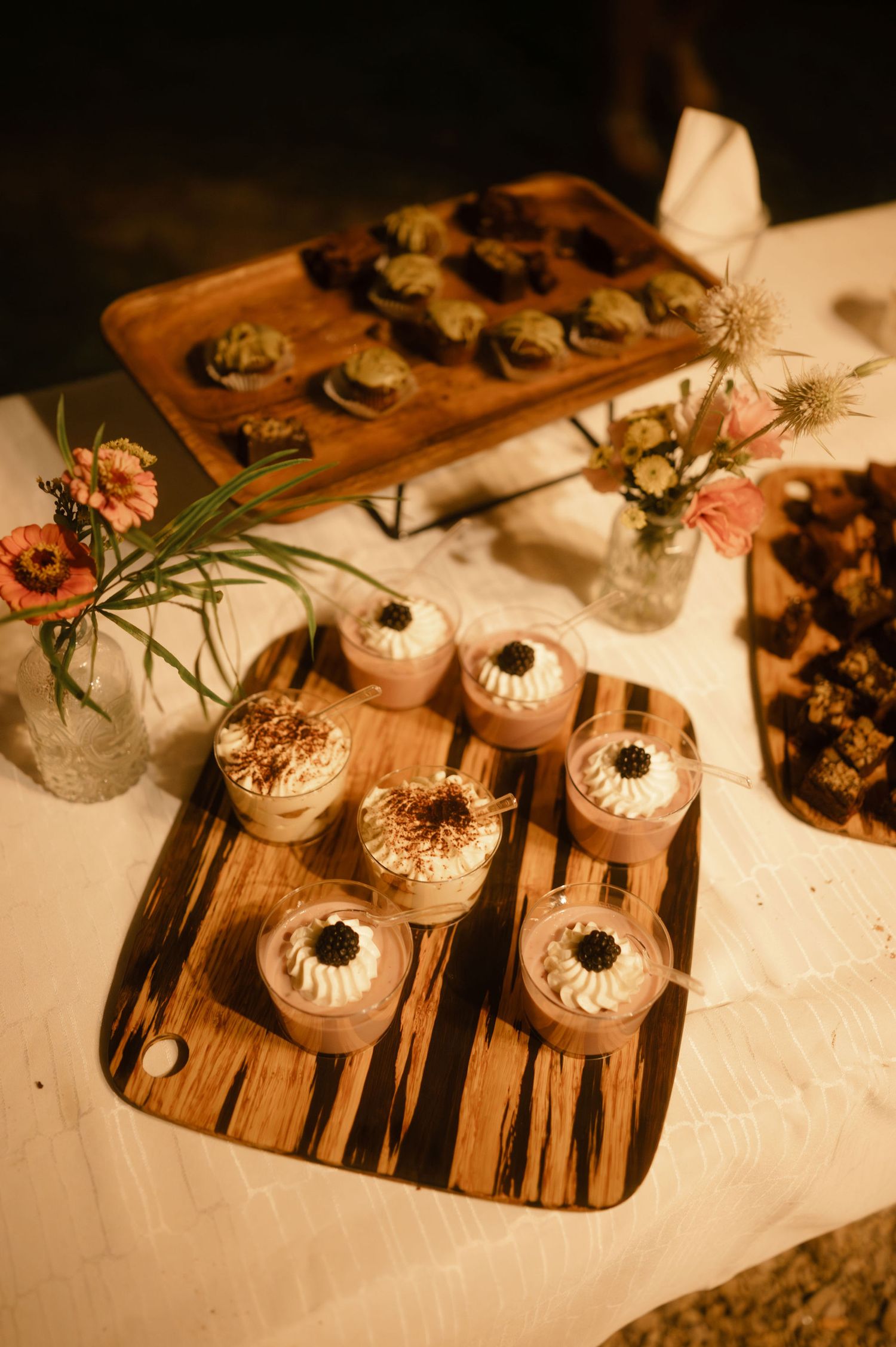 Elegant appetizers served on wooden serving boards with white garnishes and decorative elements in warm lighting.