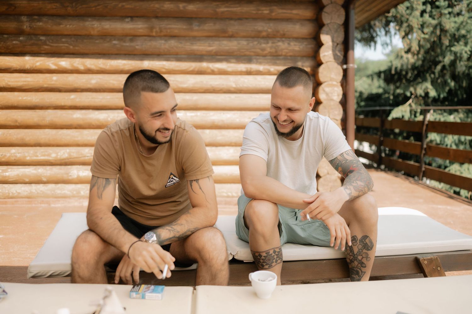 Two people sitting on wooden steps sharing laughter and conversation while enjoying a casual outdoor moment together.