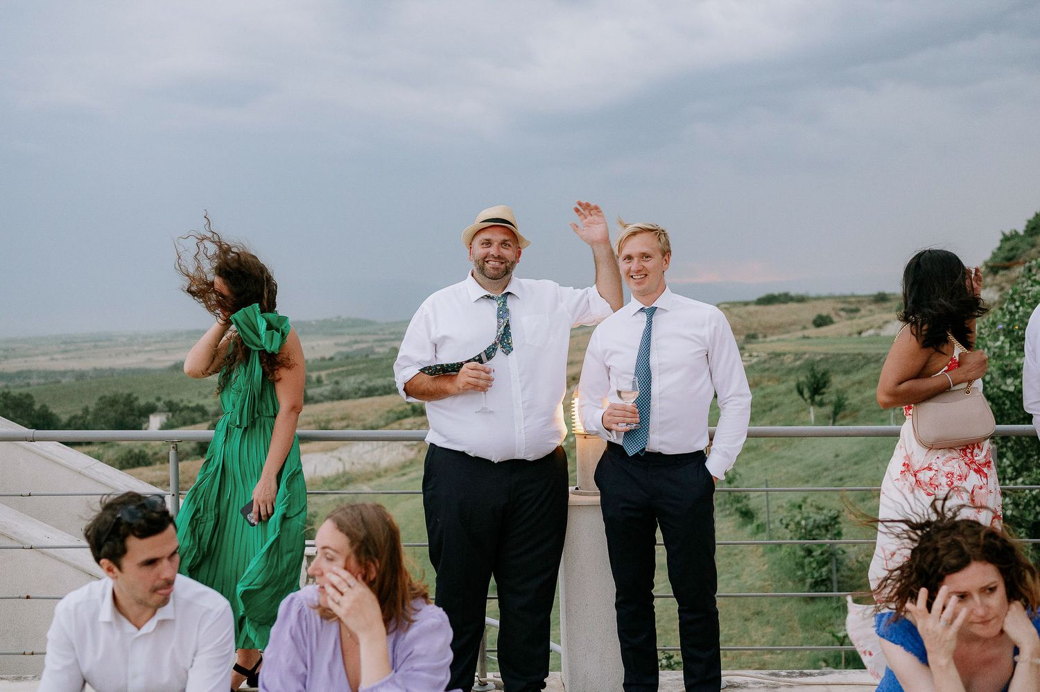 Wedding guests celebrate and dance on an outdoor terrace with scenic views.