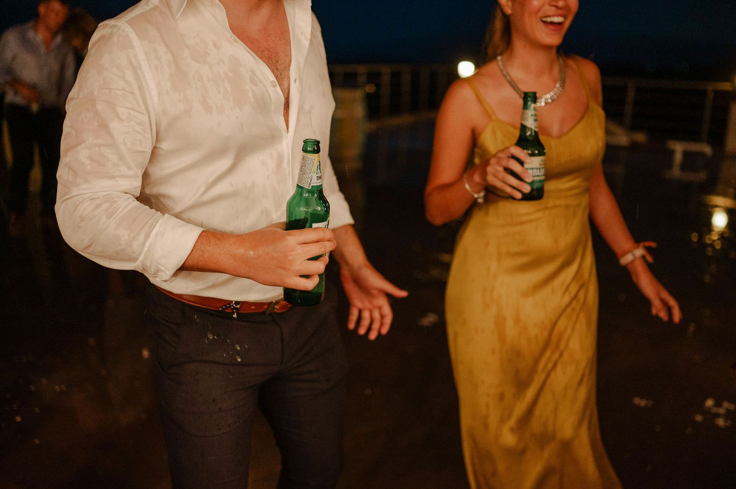 Wedding guests enjoy drinks and conversation during an outdoor evening celebration.