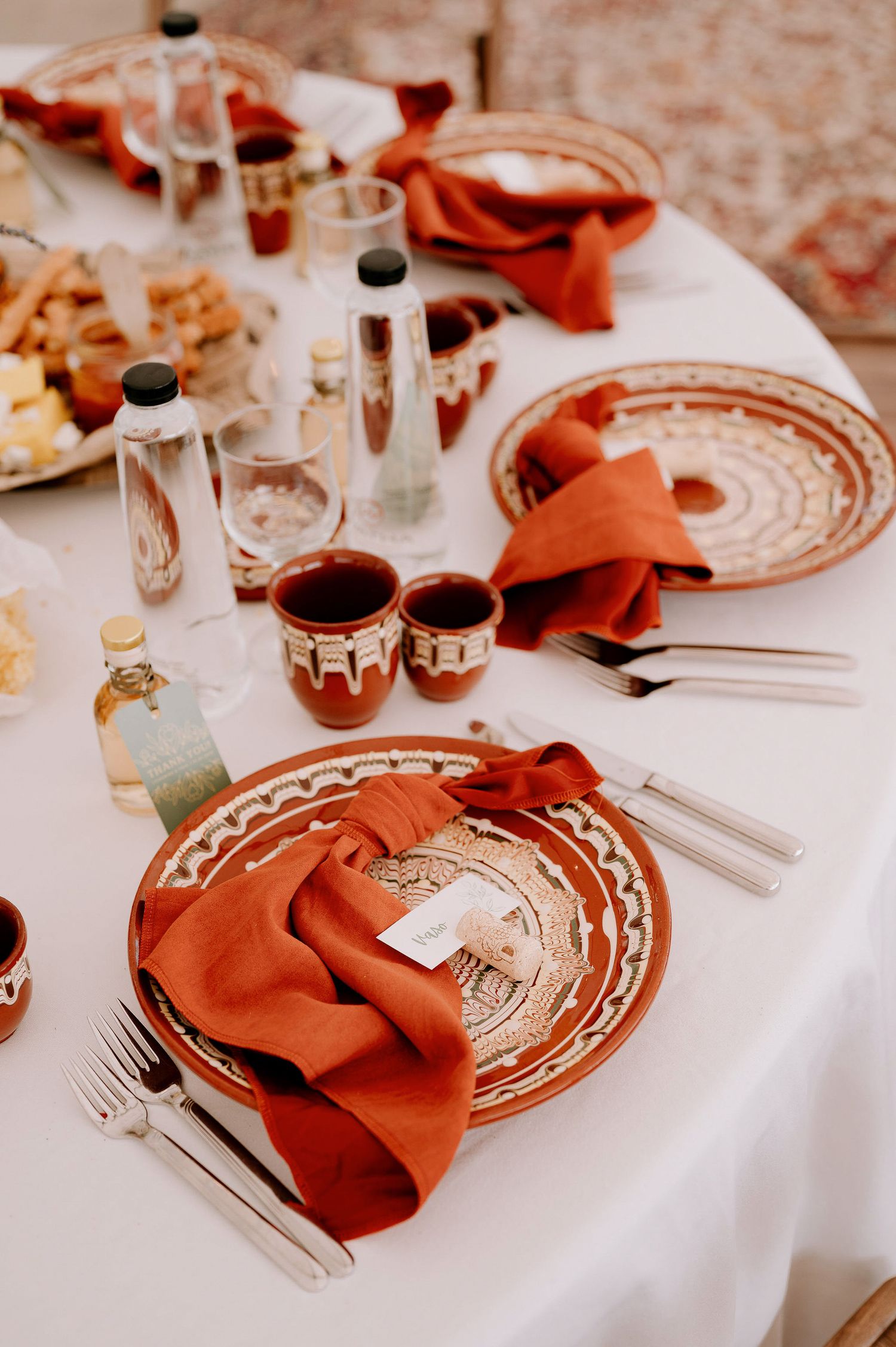 Close-up of formal place setting with burnt orange napkins and decorative plates.