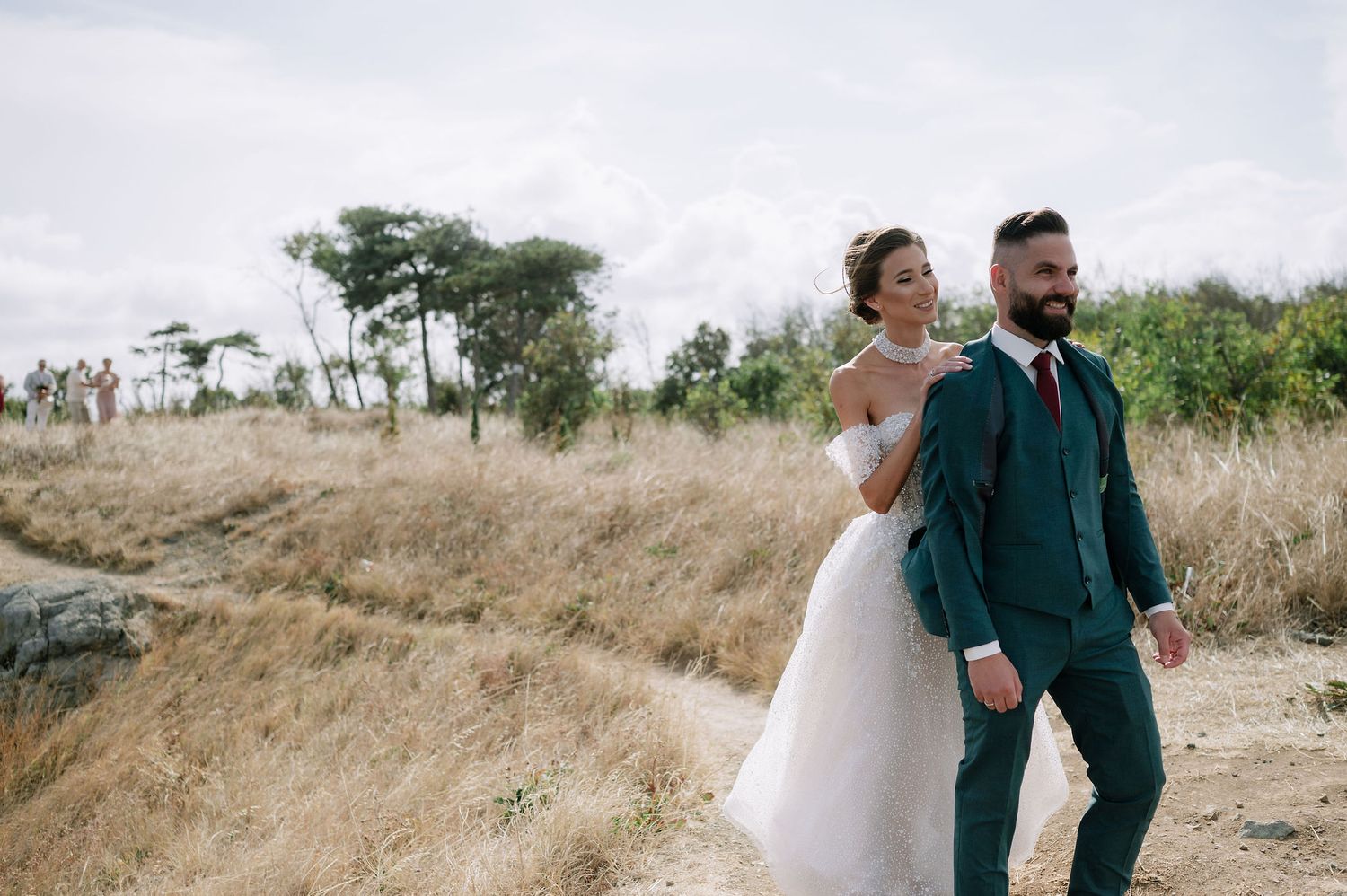 A couple walking together on a scenic hilltop path during their wedding day.