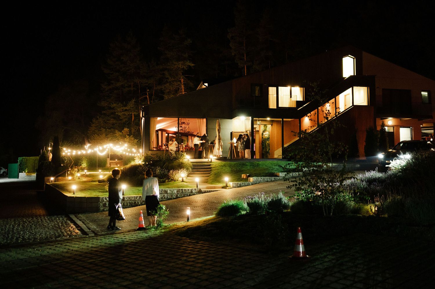 Outdoor wedding venue lit up at night with pathway lighting and illuminated buildings.