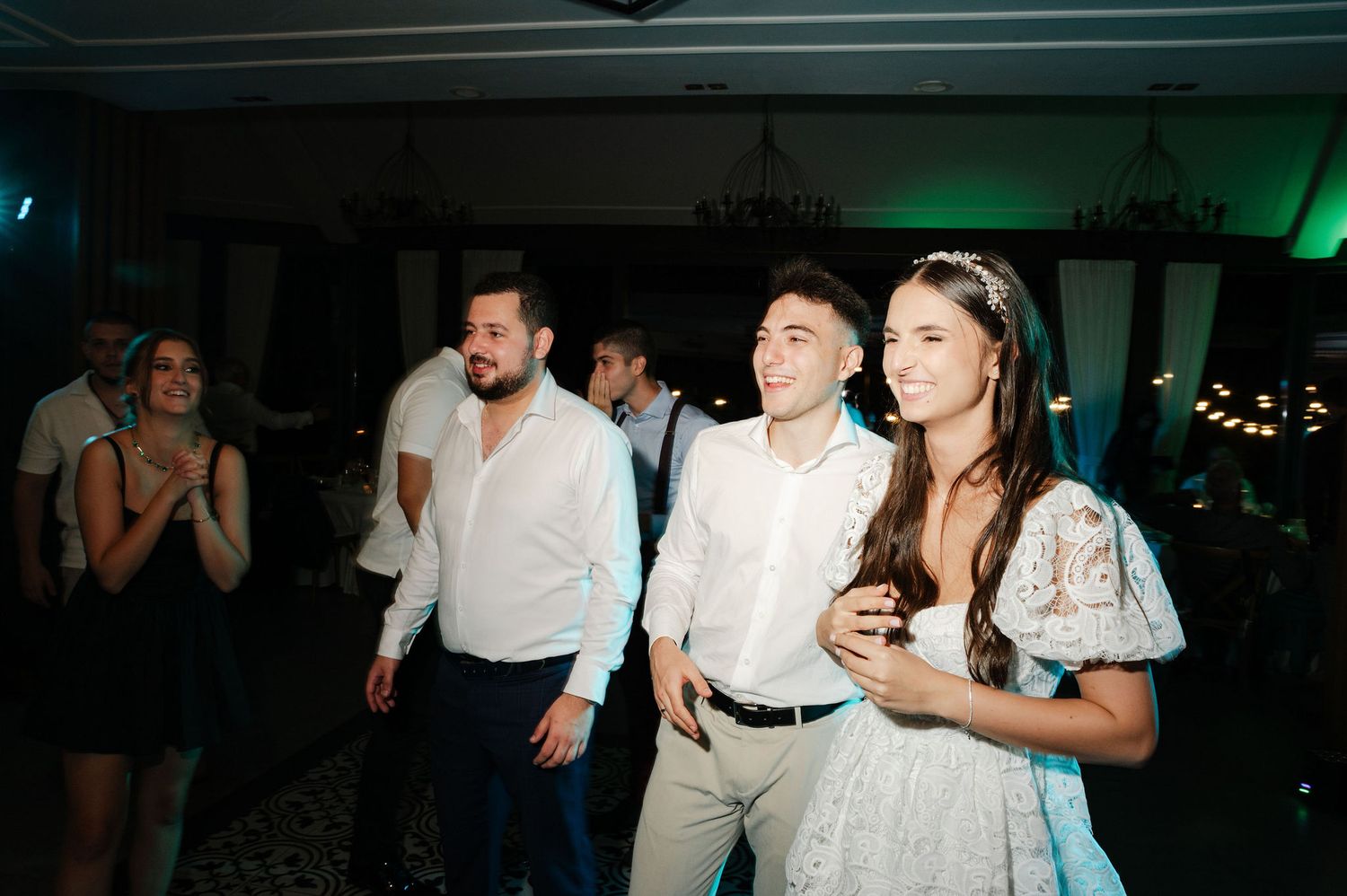 Wedding celebration with green uplighting and guests dancing in formal attire.
