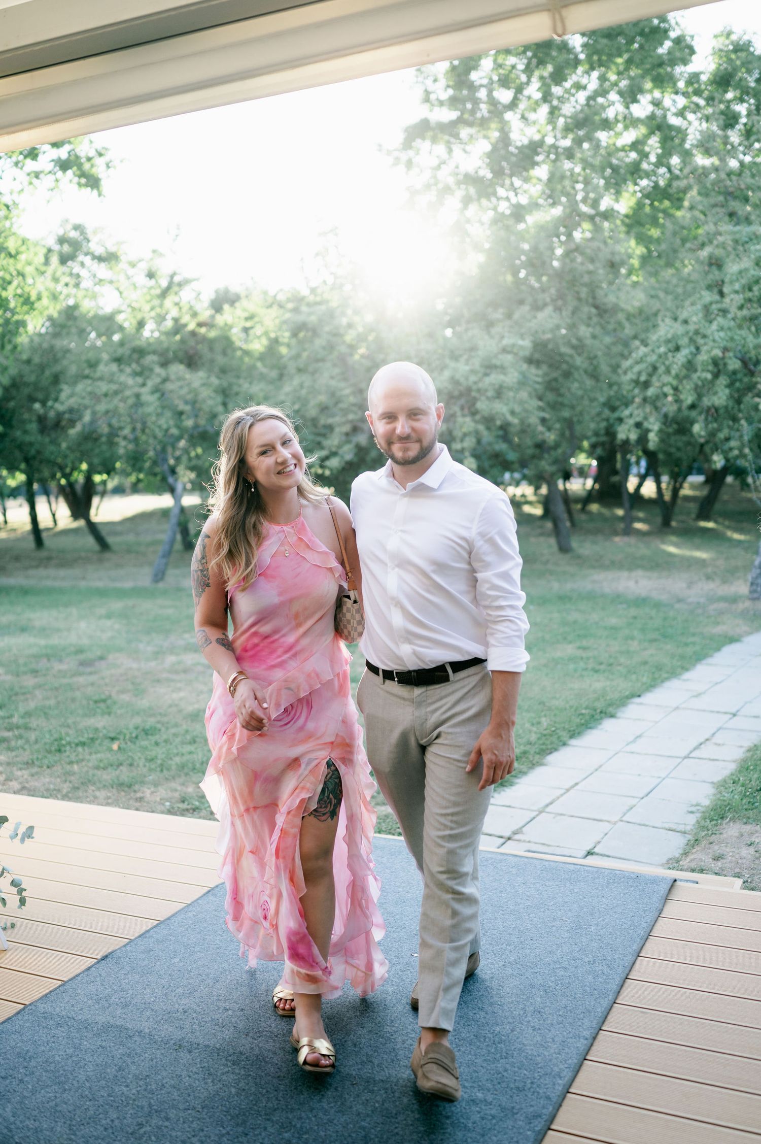 A couple dancing and laughing together outdoors on a wooden walkway surrounded by trees.
