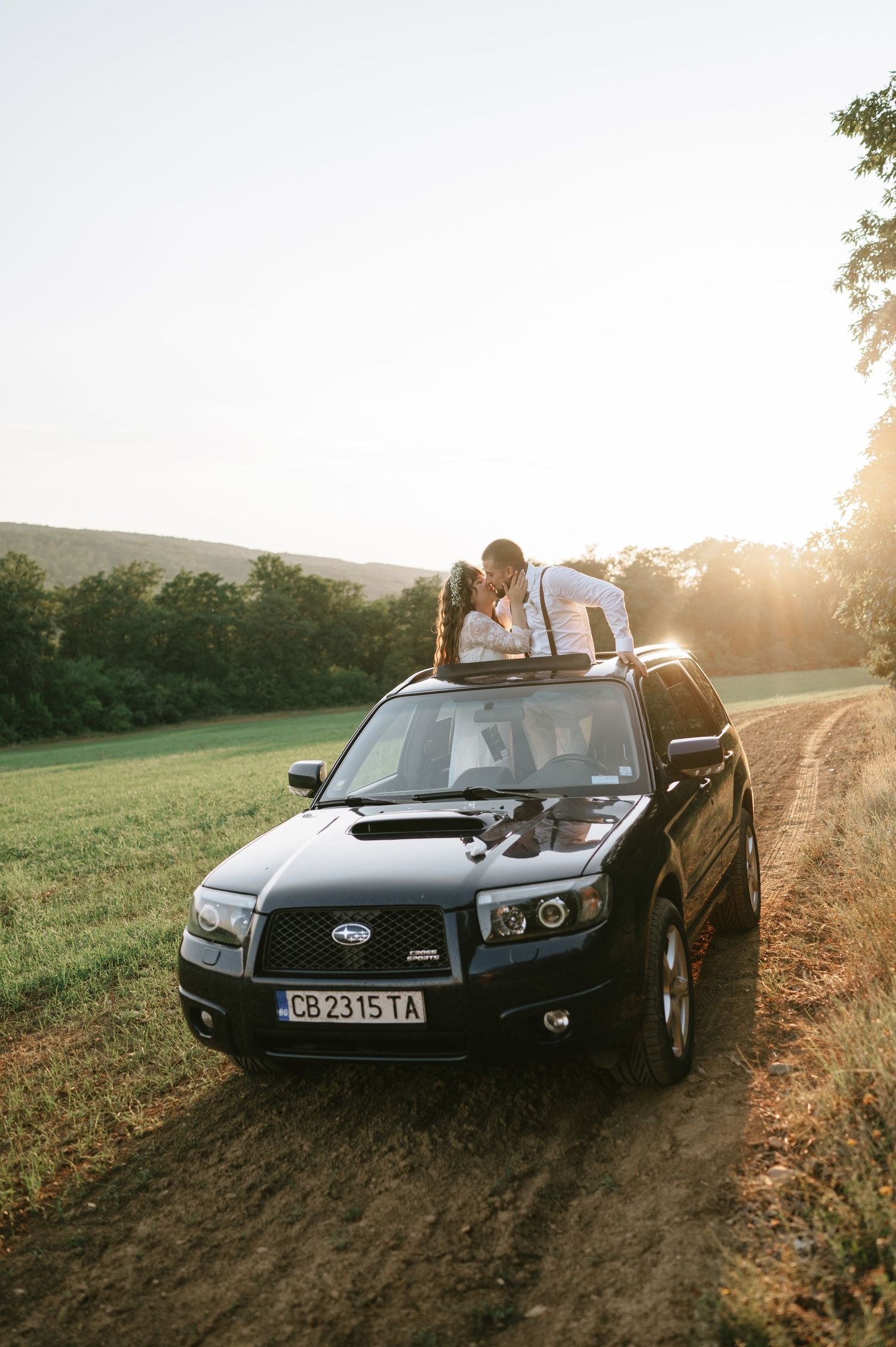 A black Subaru car parked on a dirt road during sunset with scenic views.