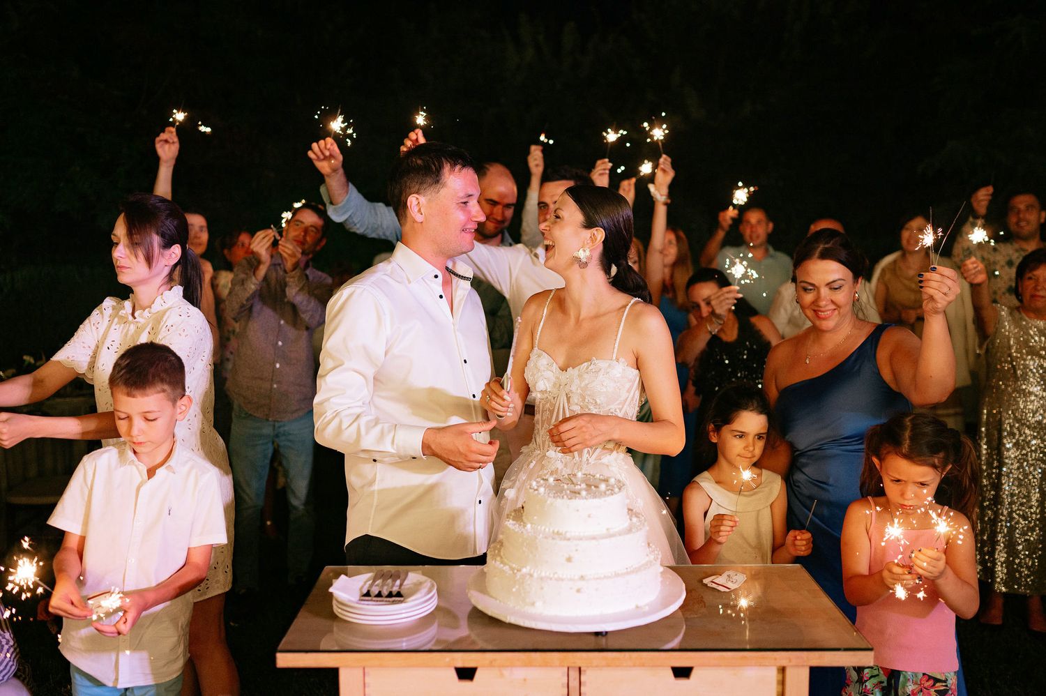 Wedding party and guests enjoying festivities during an outdoor evening celebration.