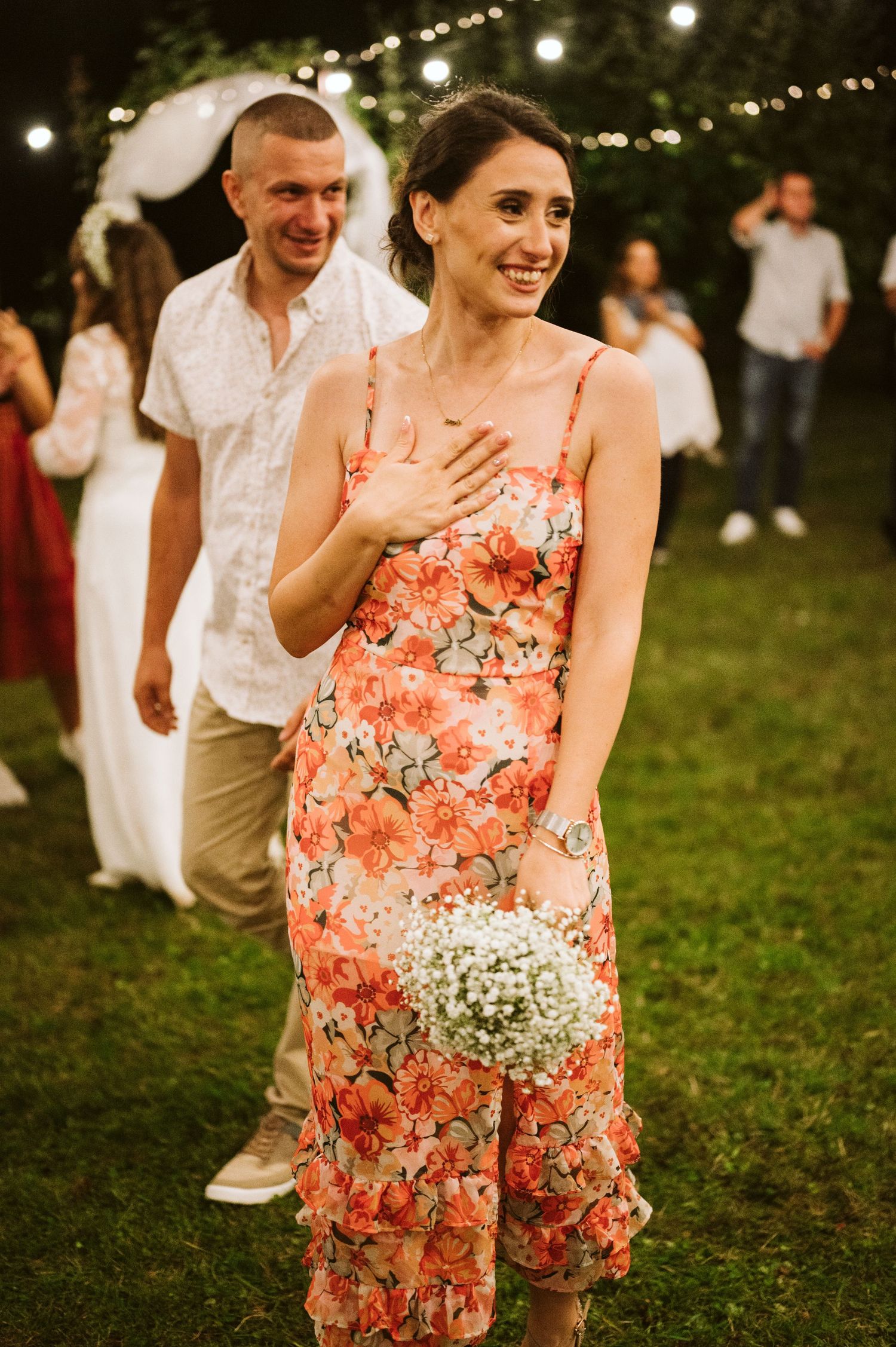 Wedding guests celebrate on the dance floor under string lights at an outdoor reception.