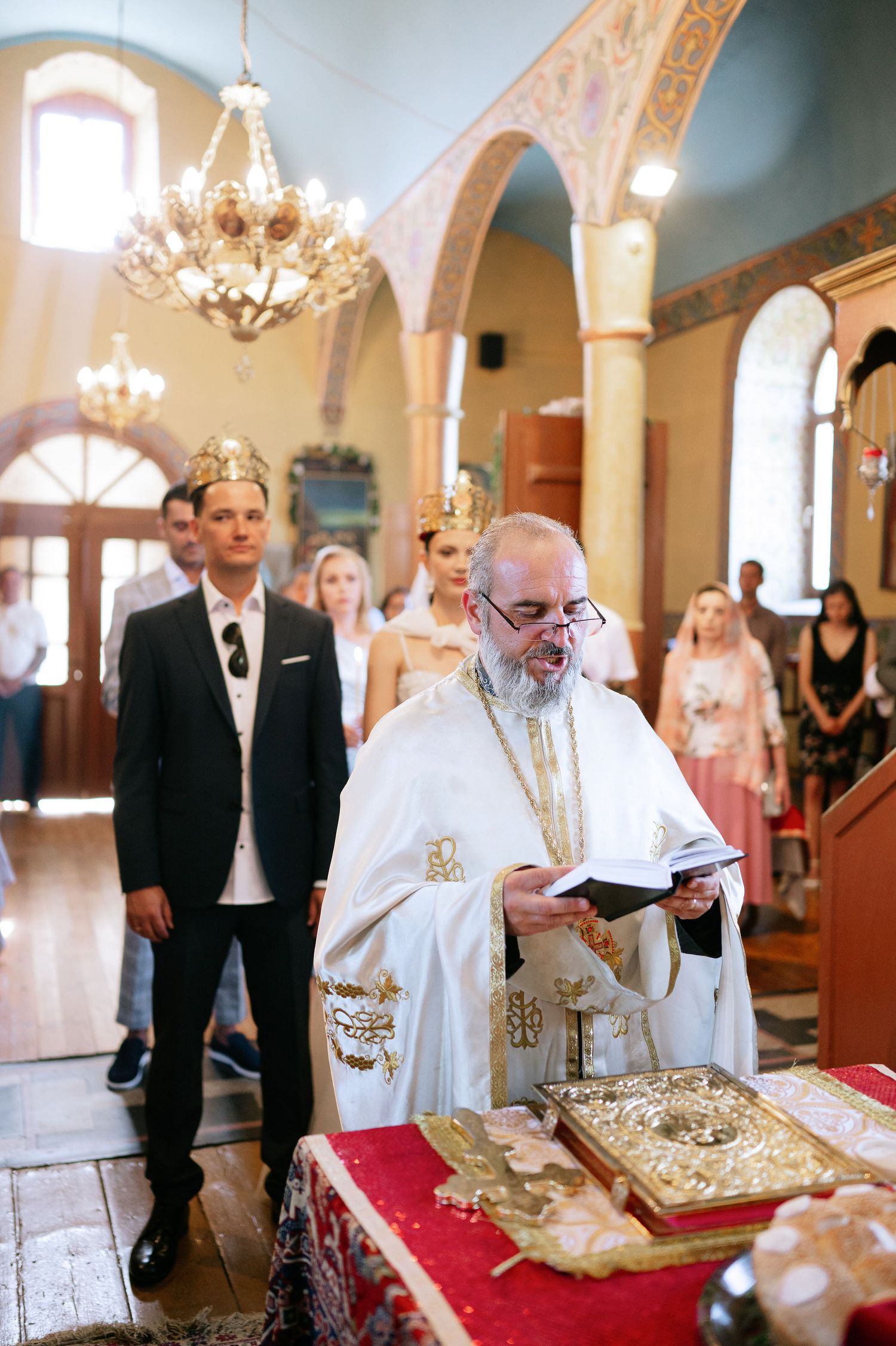 Religious ceremony with clergy in white robes performing traditional rituals at an ornate altar.
