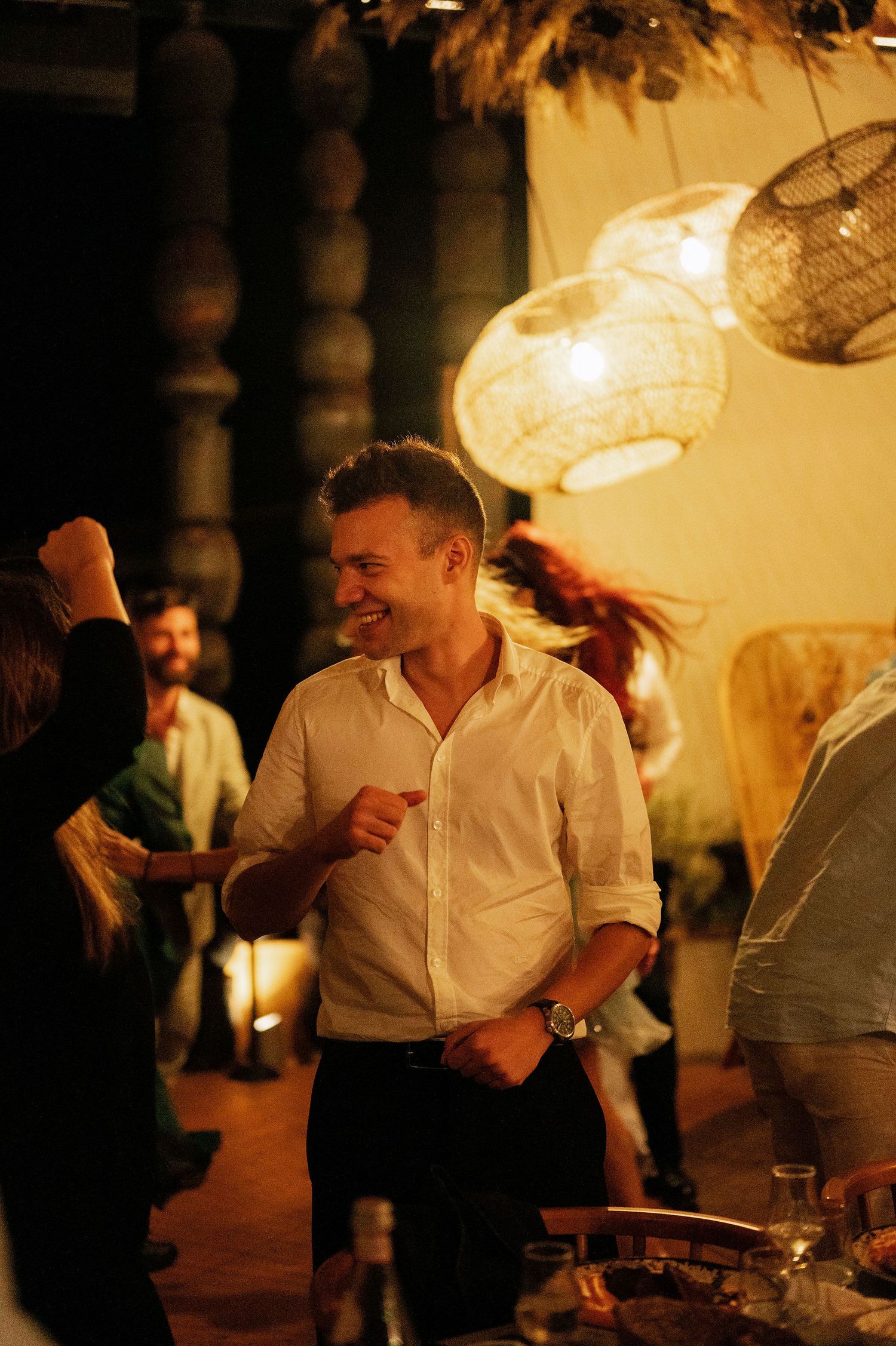 Guests mingling and socializing at an evening indoor celebration with warm lighting.