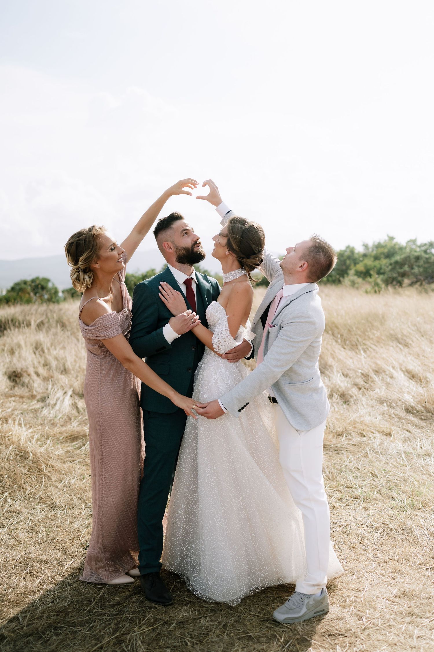 Joyful wedding party celebrating and laughing together in a golden field.