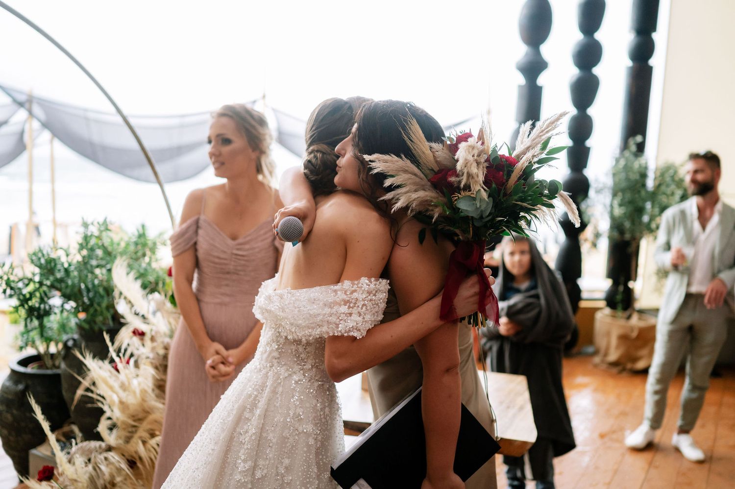 Wedding ceremony space features elegant white draping and ornate black pillars with natural light.