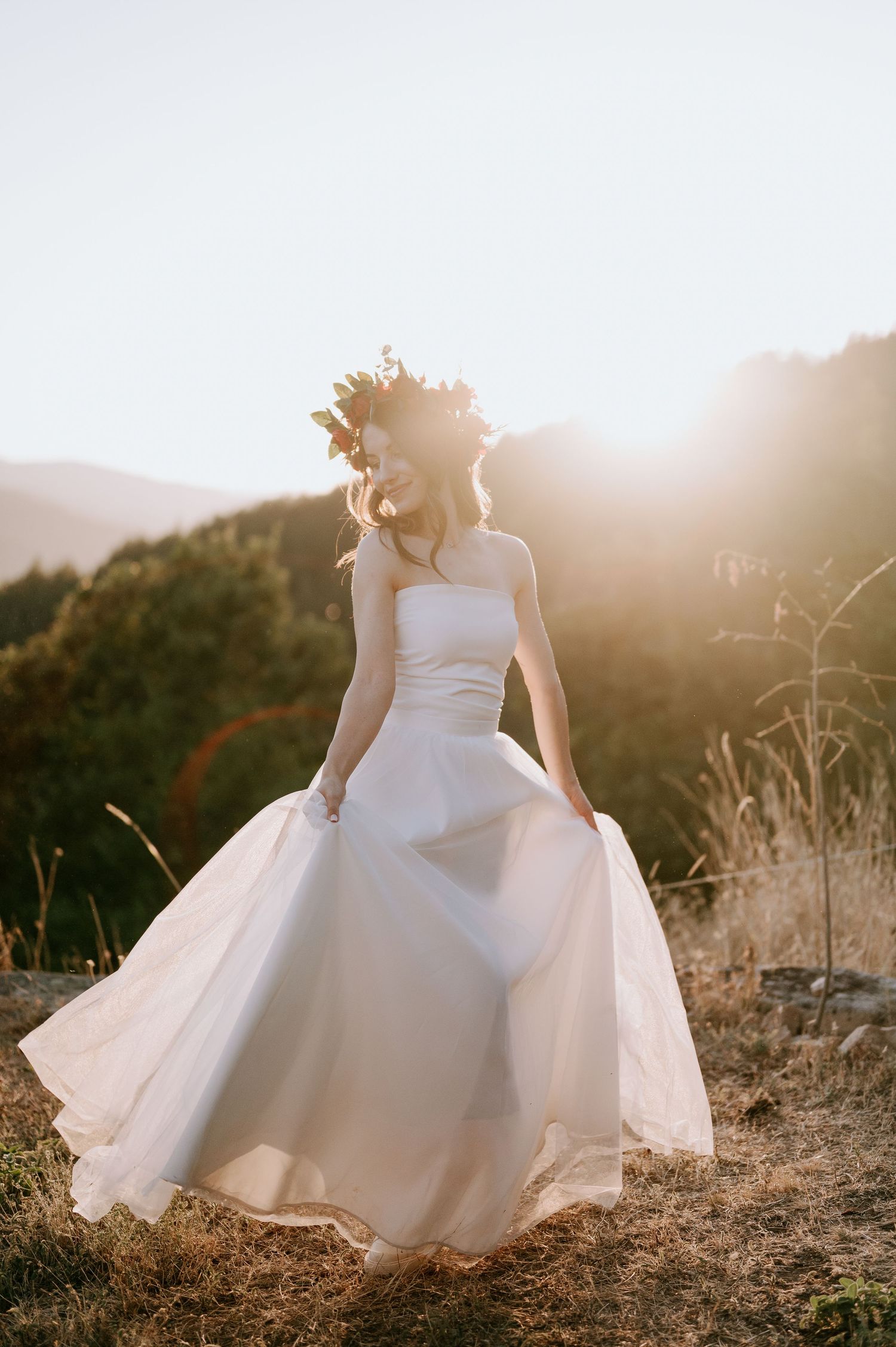 Ethereal white dress spins against warm sunlight and dry grass on a hillside.