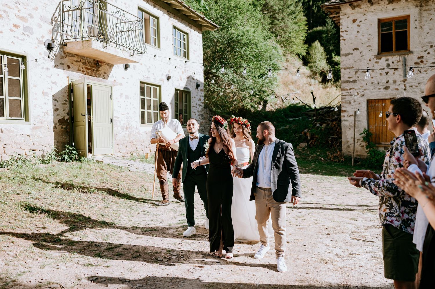 Wedding celebration in progress outside rustic stone venue with mountain views.