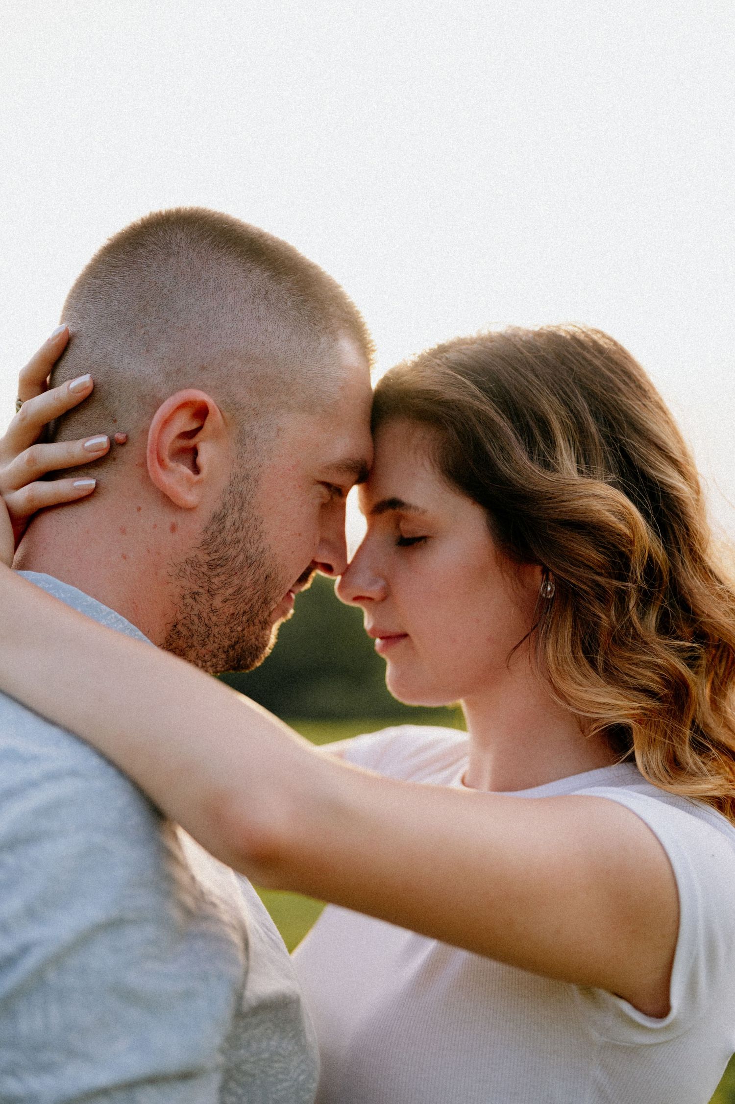 Couple sharing romantic moment with arms wrapped around each other outdoors.