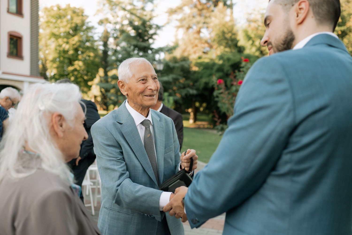 Wedding guests share emotional embraces and congratulations during an outdoor autumn ceremony.