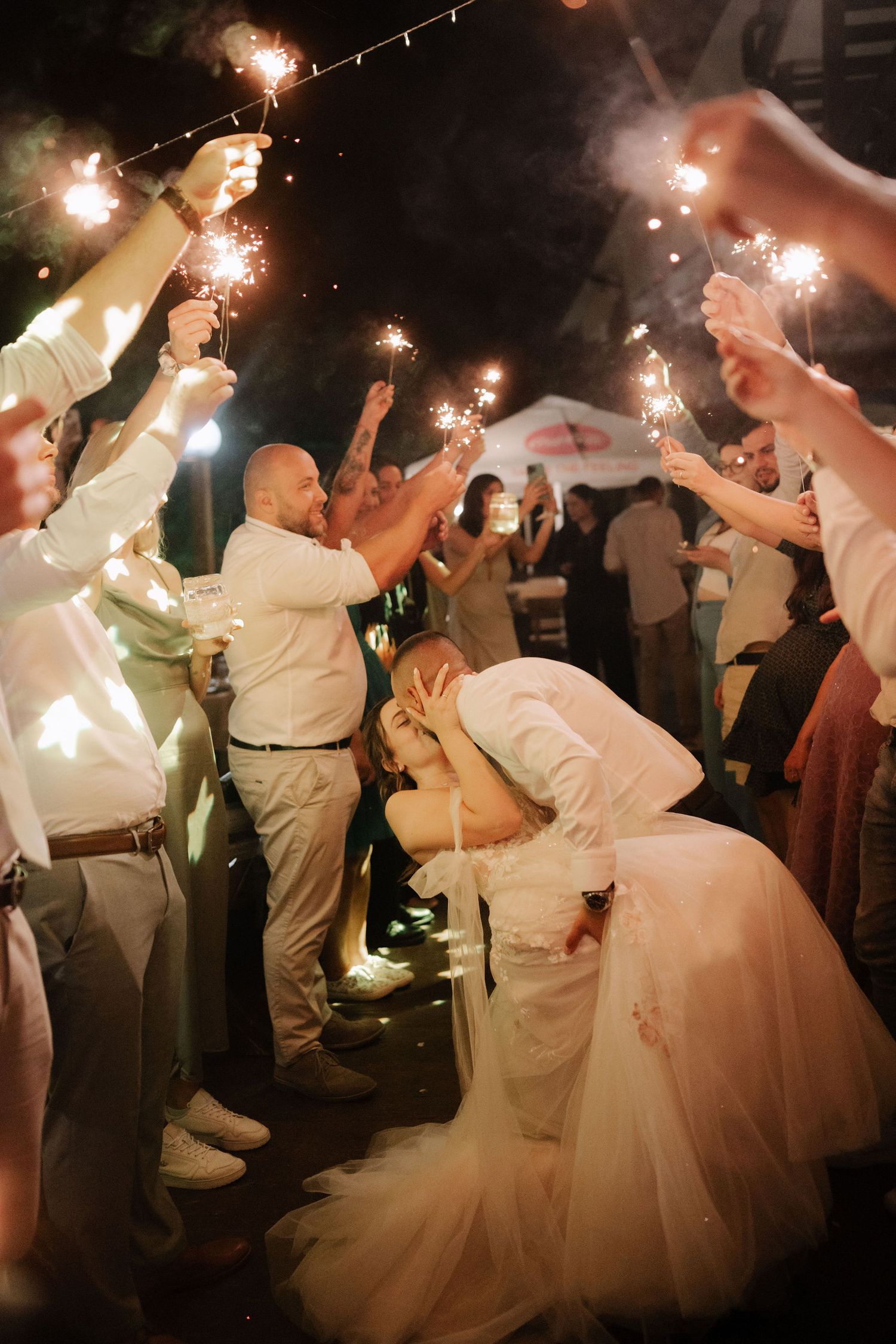 Wedding guests dance and celebrate with sparklers at an evening reception creating a magical atmosphere.