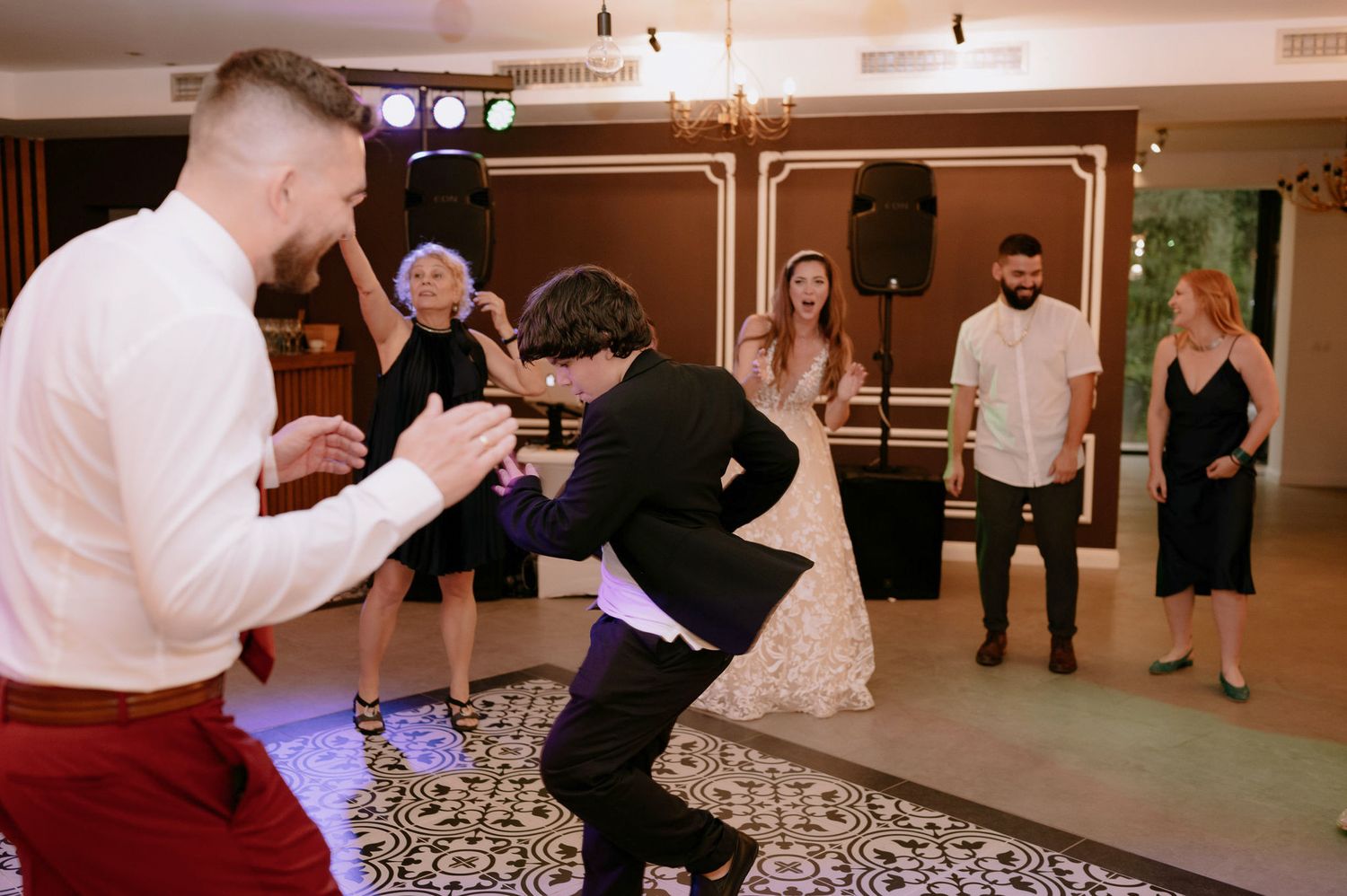 Couples dance together on a patterned floor during what appears to be a ballroom dance class or social event.