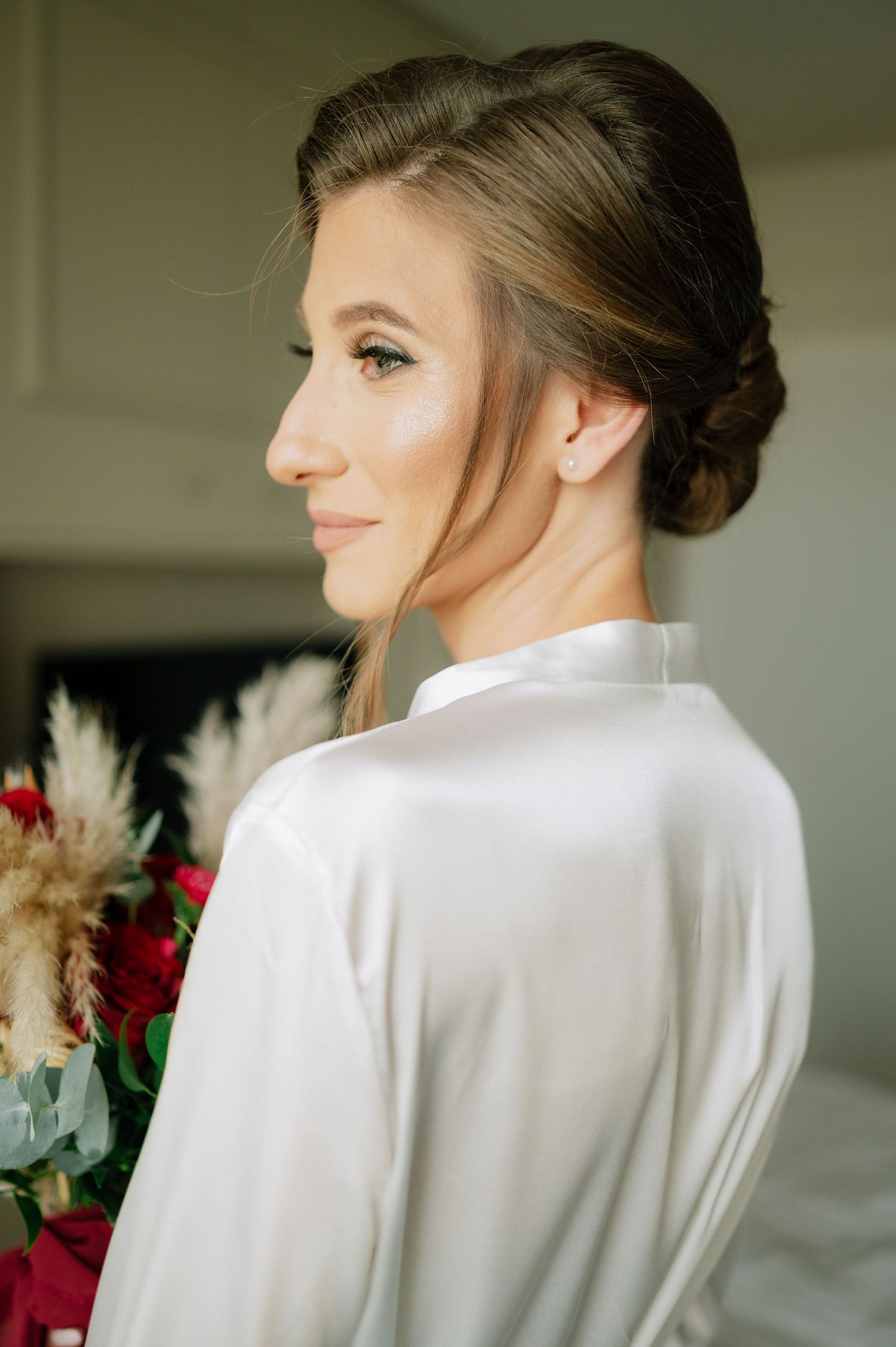 Elegant bridal preparations captured in soft natural lighting with white robe.