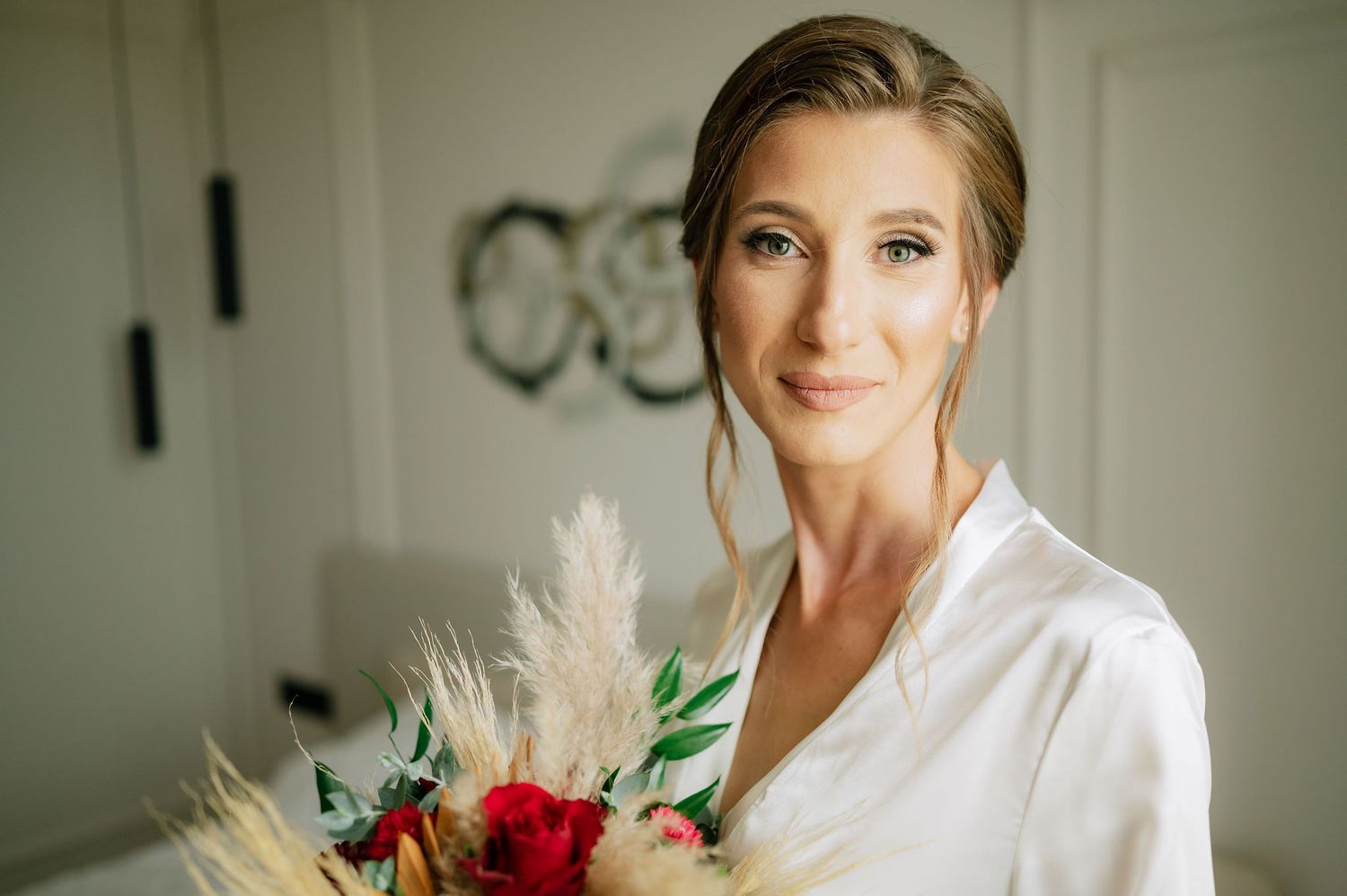 Elegant wedding morning preparations with white robes and floral bouquets.