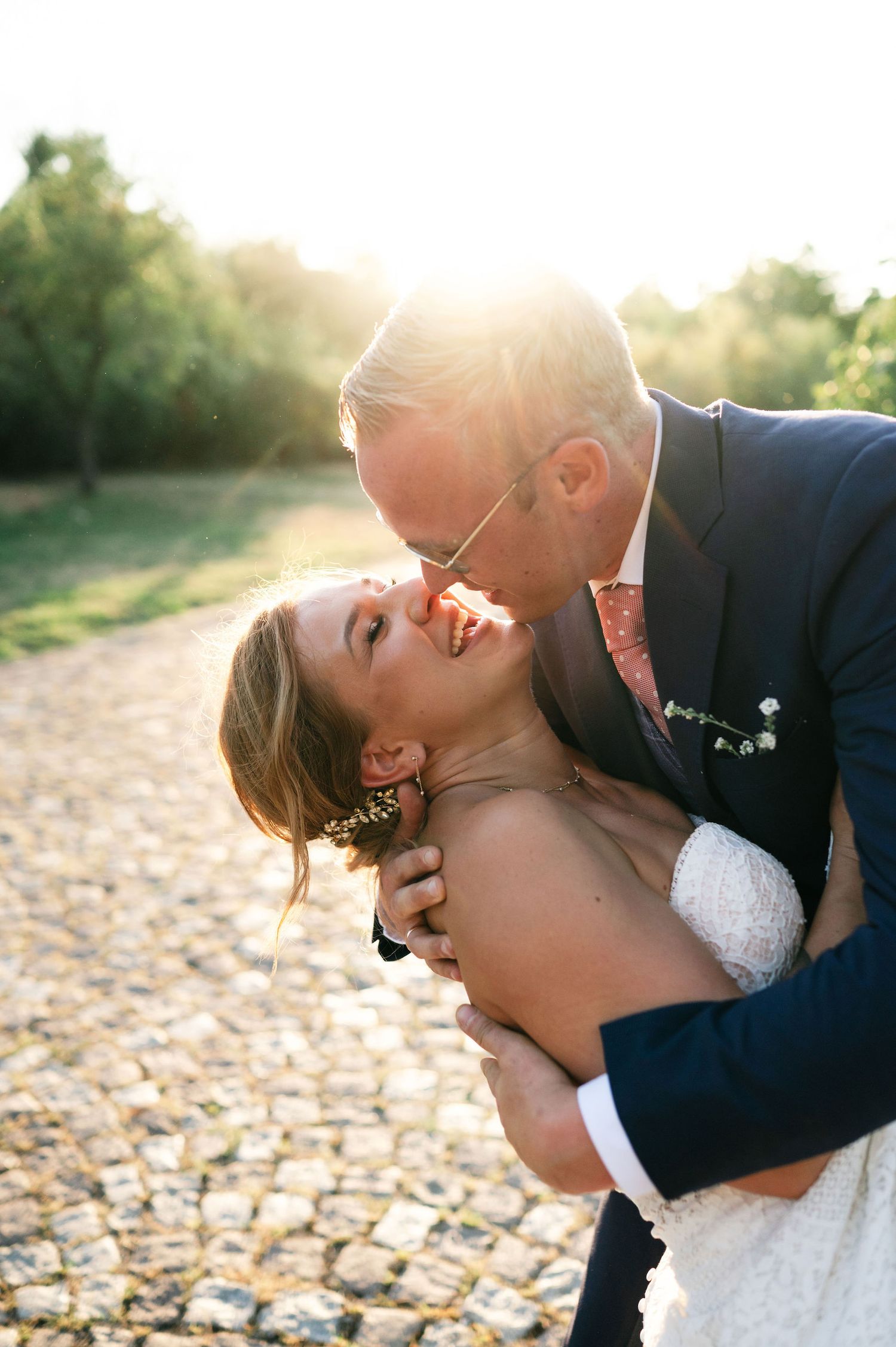 A joyful wedding couple shares a passionate moment in the warm evening sunlight.