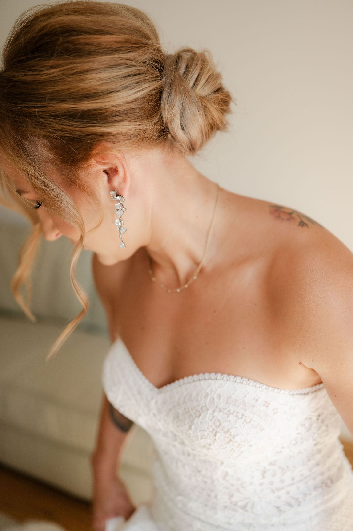 Close-up details of a bride's elegant updo hairstyle and dangling earrings.