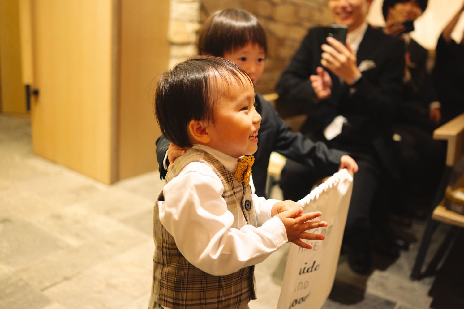 Guests at a formal event engaging with each other in a room with stone walls and warm lighting.