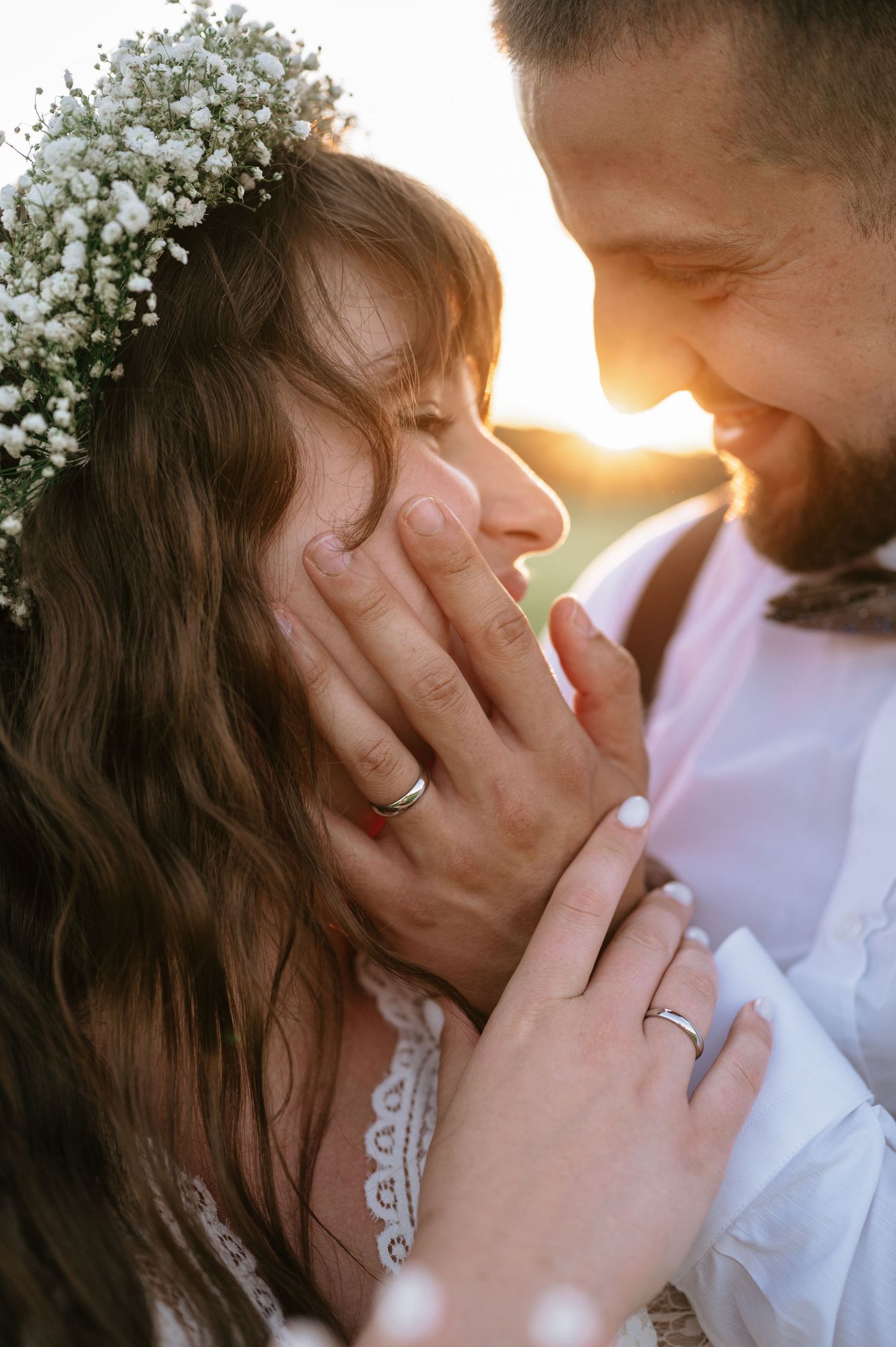 Intimate wedding couple shares tender moment at golden hour with floral details.