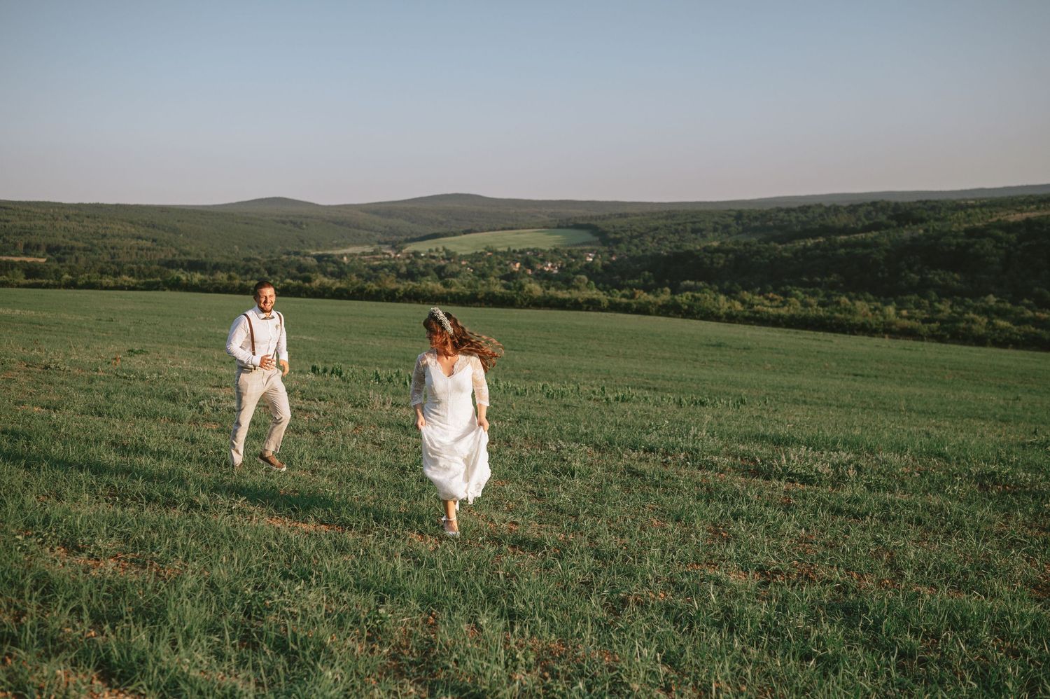 Rolling green hills provide a scenic backdrop for an outdoor wedding celebration.