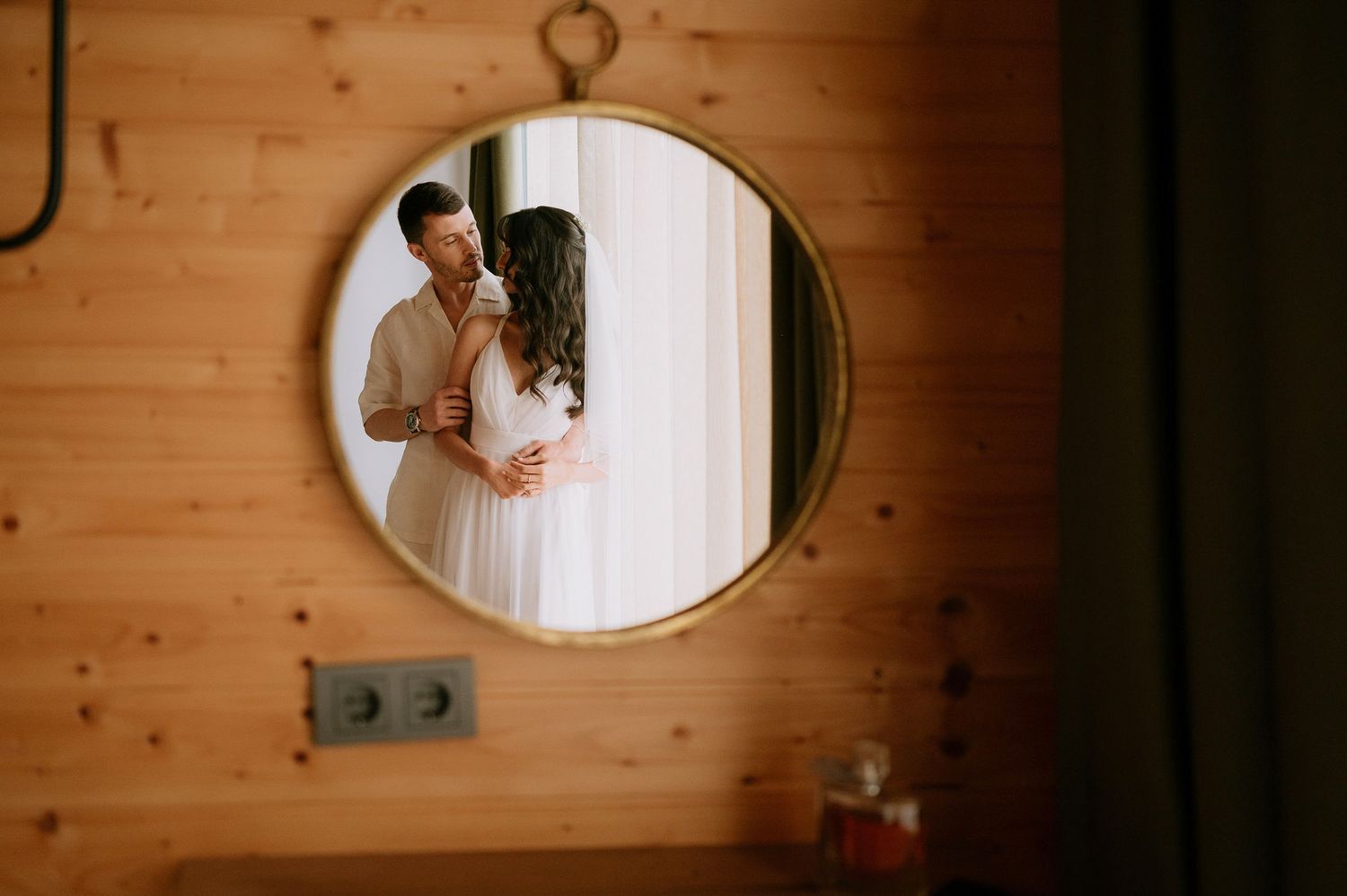 Artistic mirror reflection of a romantic moment between a couple in a rustic cabin setting.